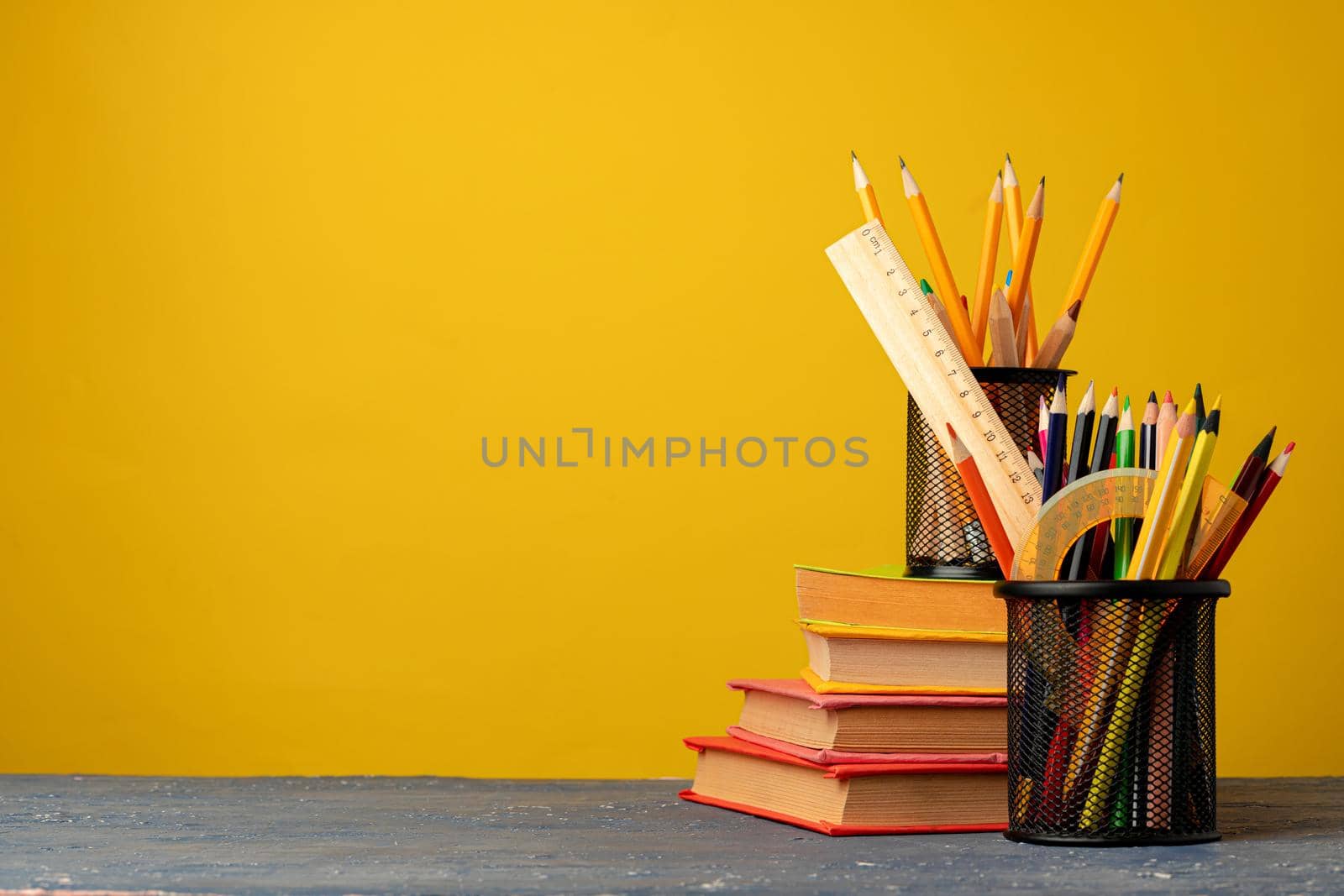 Office cup with pencils and stationery against yellow background front view