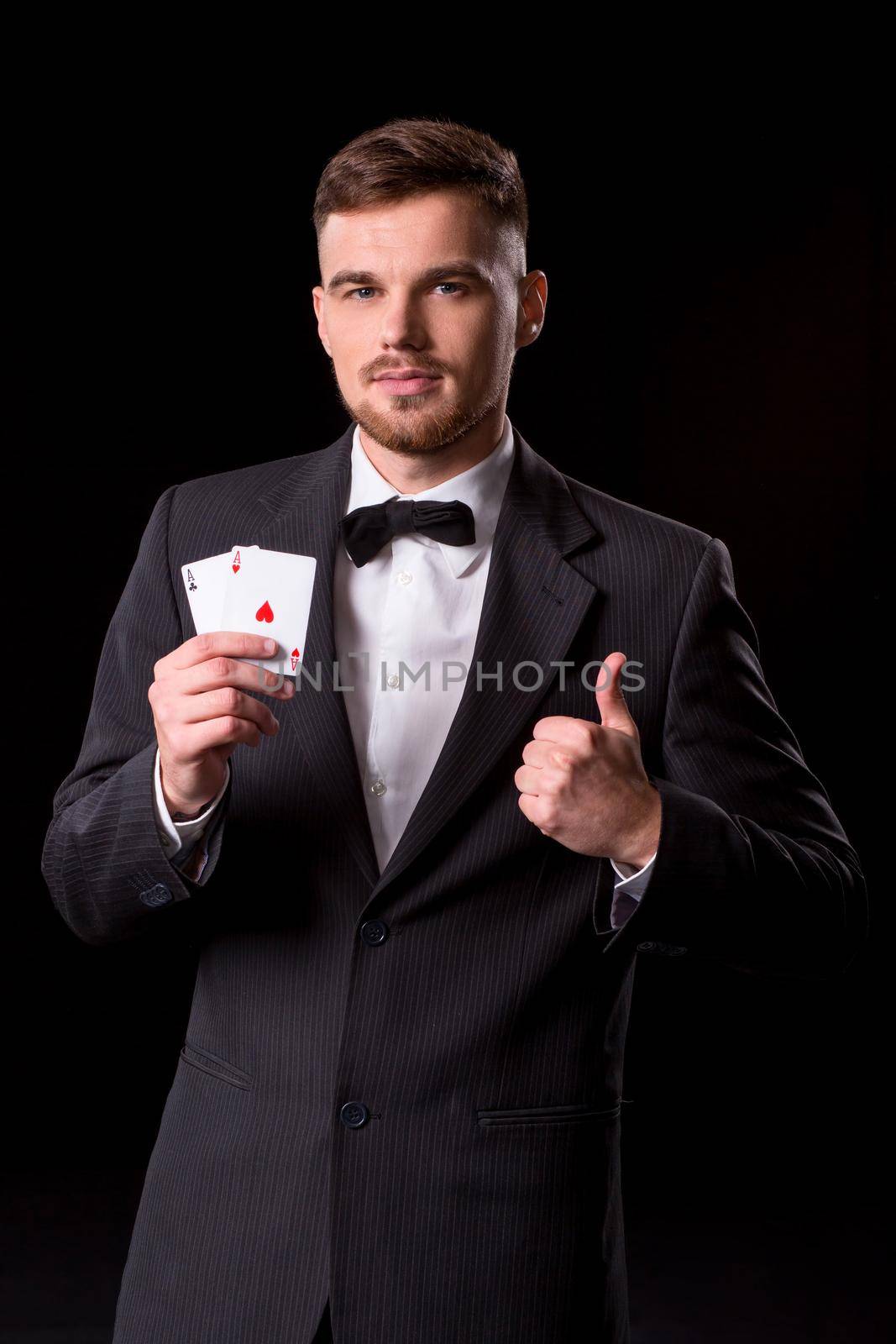 man in a suit posing with cards for gambling on black background