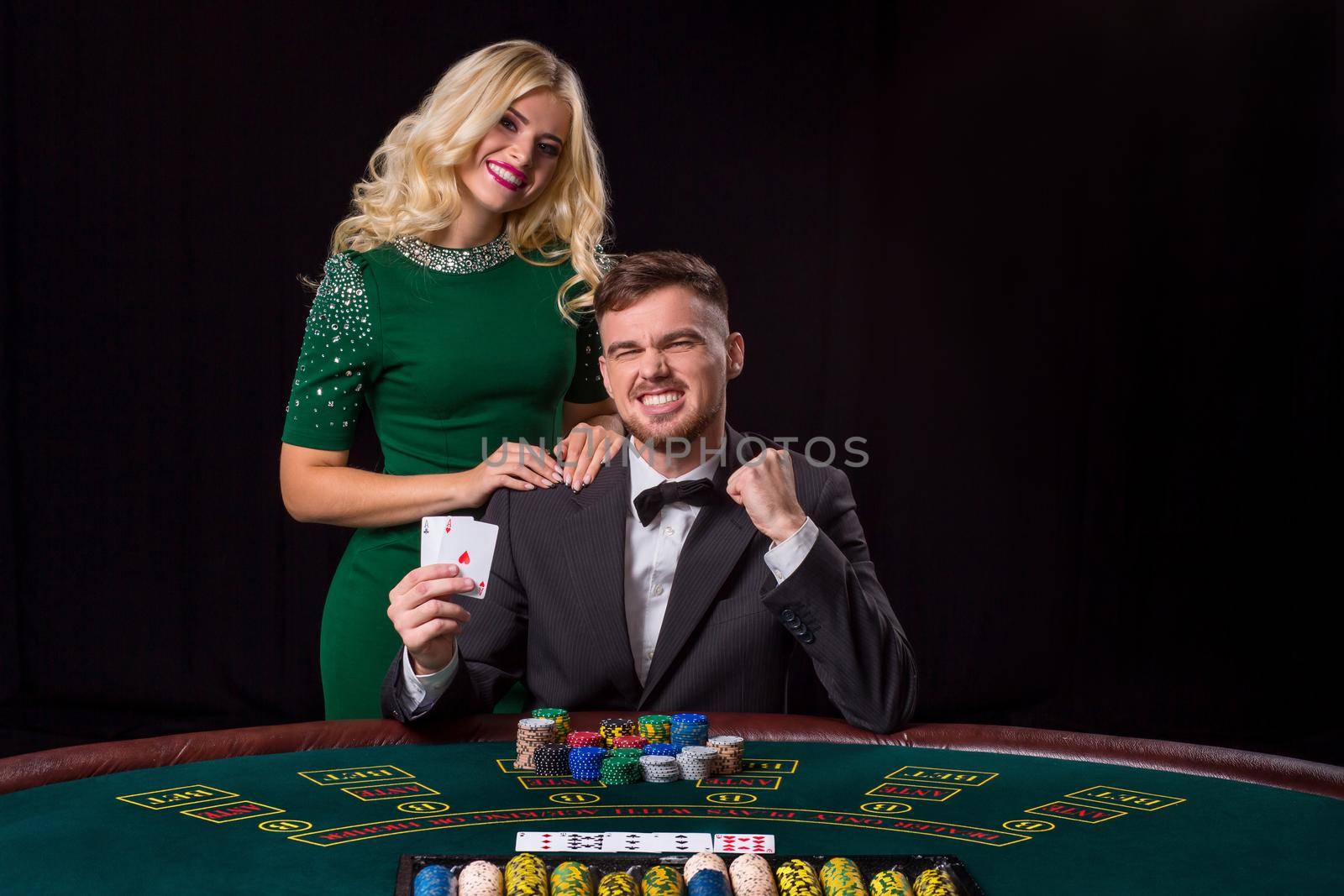 couple playing poker at the green table. The blonde girl and a guy in a suit. happy win, two