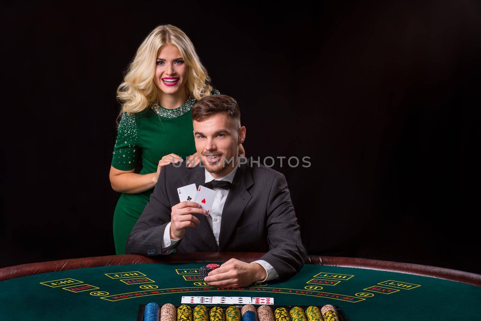 couple playing poker at the green table. The blonde girl and a guy in a suit. happy win, two