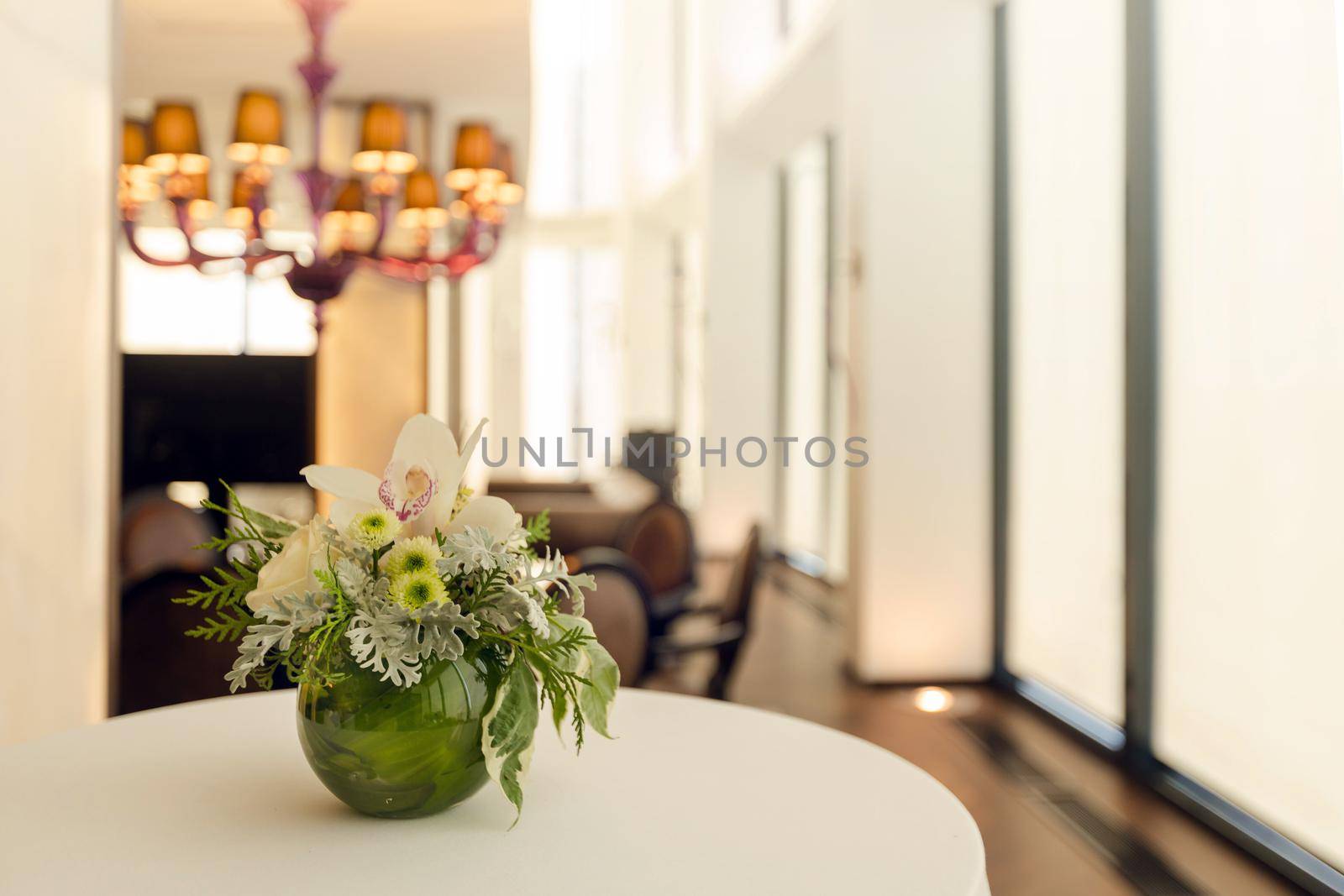 Fancy bouquet with exotic flowers in green round vase on table in reception hall