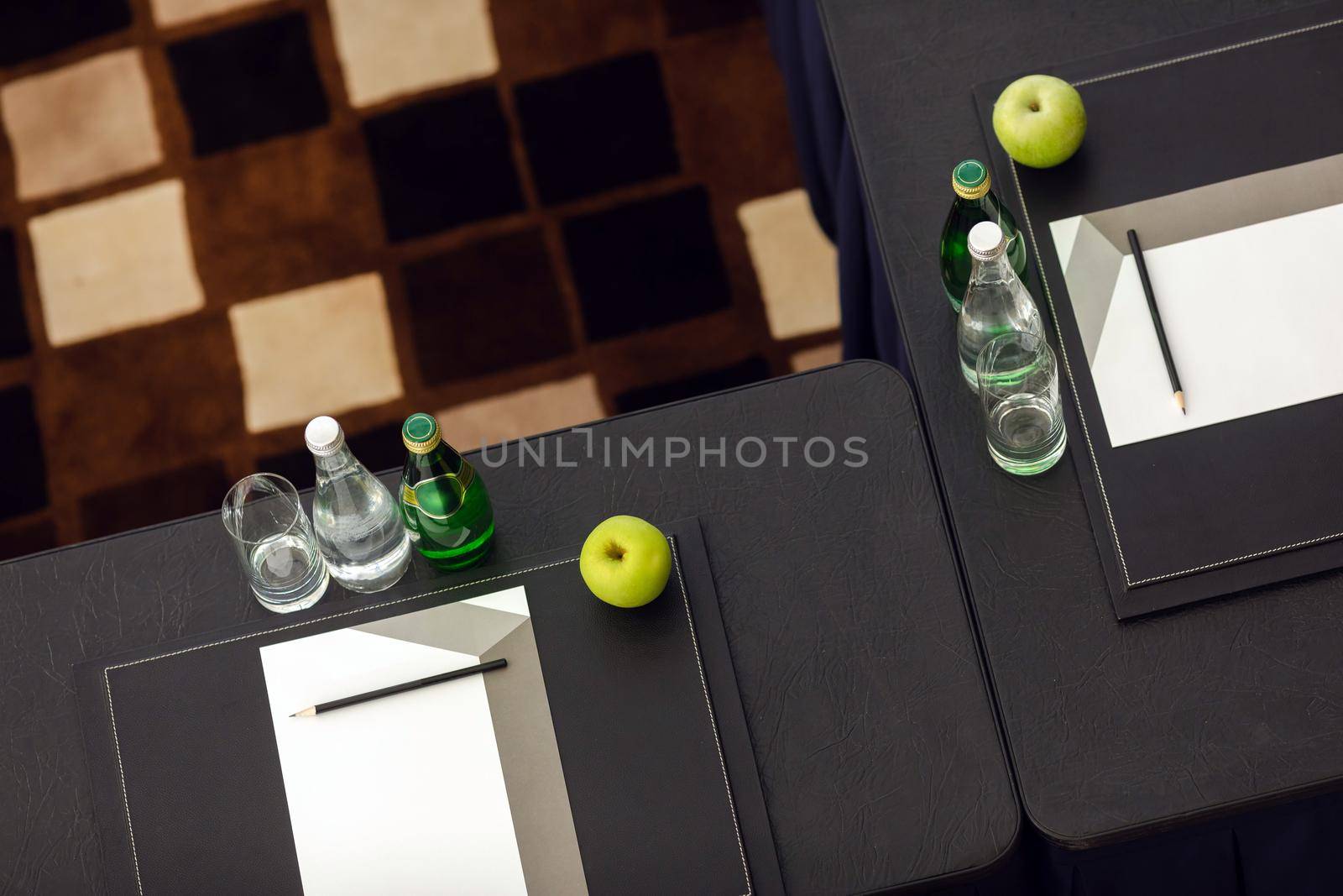 Arranged desks with water and apple next to stationery in class by Demkat