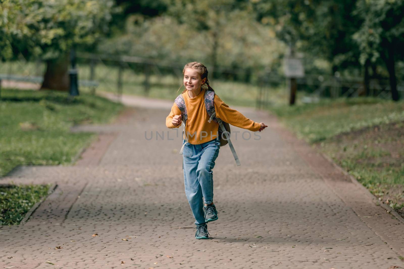 Pretty school girl with backpack running in the park after lessons. Sweet child kid at autumn outdoors