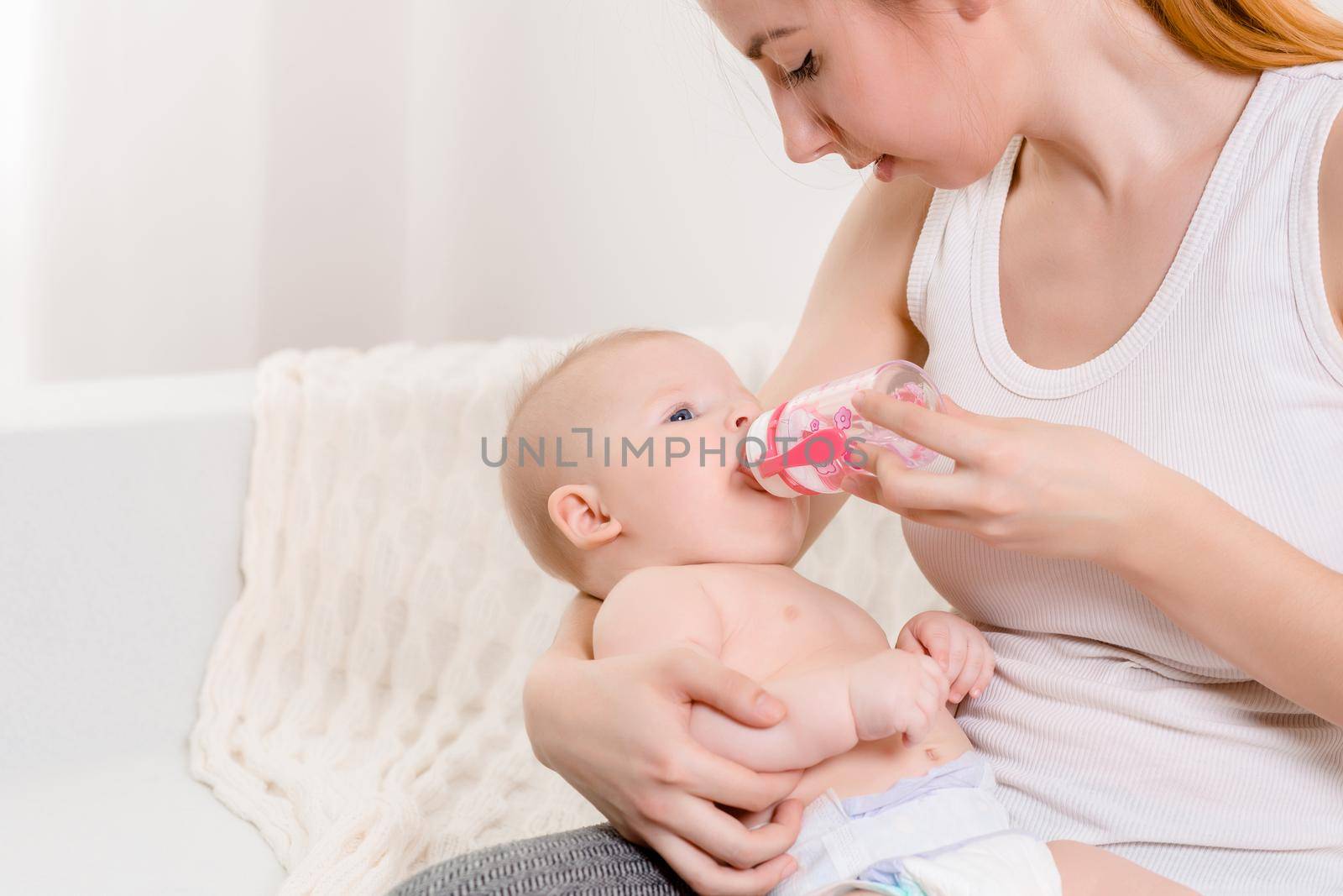 Feeding Baby. Baby eating milk from the bottle. Mother Feeds Her Newborn Baby