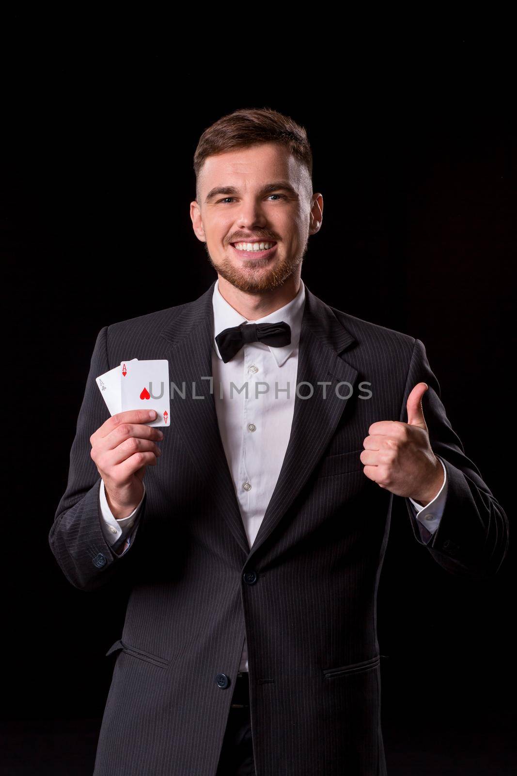 man in a suit posing with cards for gambling on black background