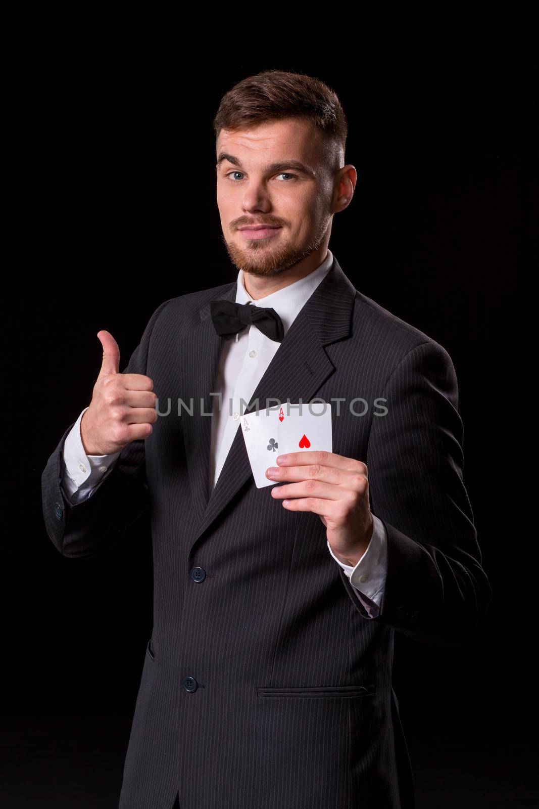 man in a suit posing with cards for gambling on black background