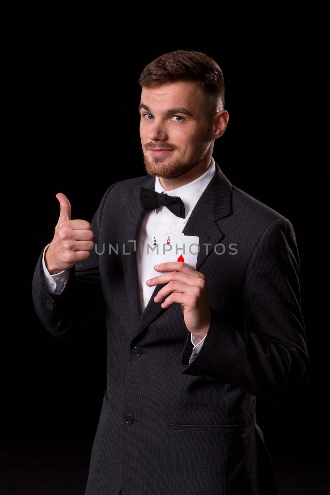 man in a suit posing with cards for gambling on black background