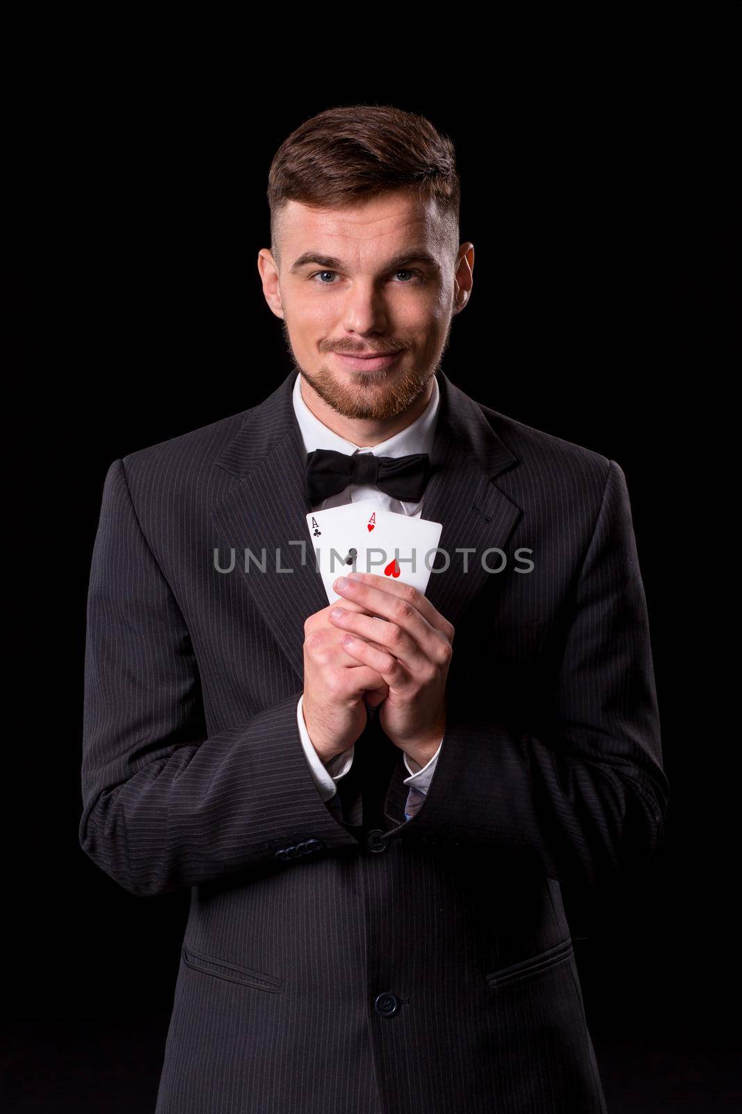 man in a suit posing with cards for gambling on black background