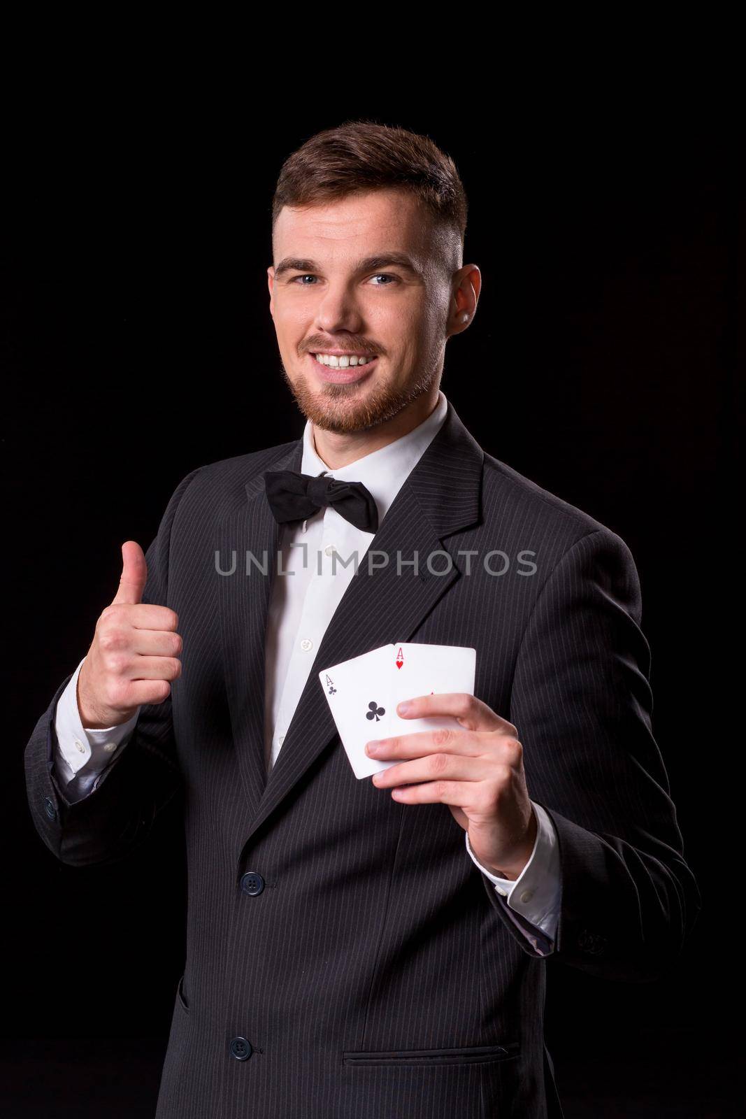 man in a suit posing with cards for gambling on black background