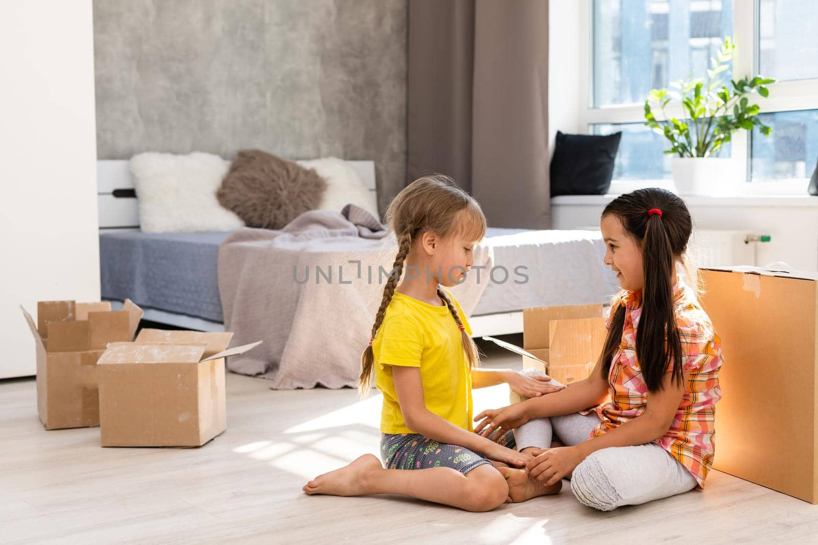 Excited funny kids girls running inside luxury big modern house on moving day, cute children entering exploring new home, happy young family buying real estate
