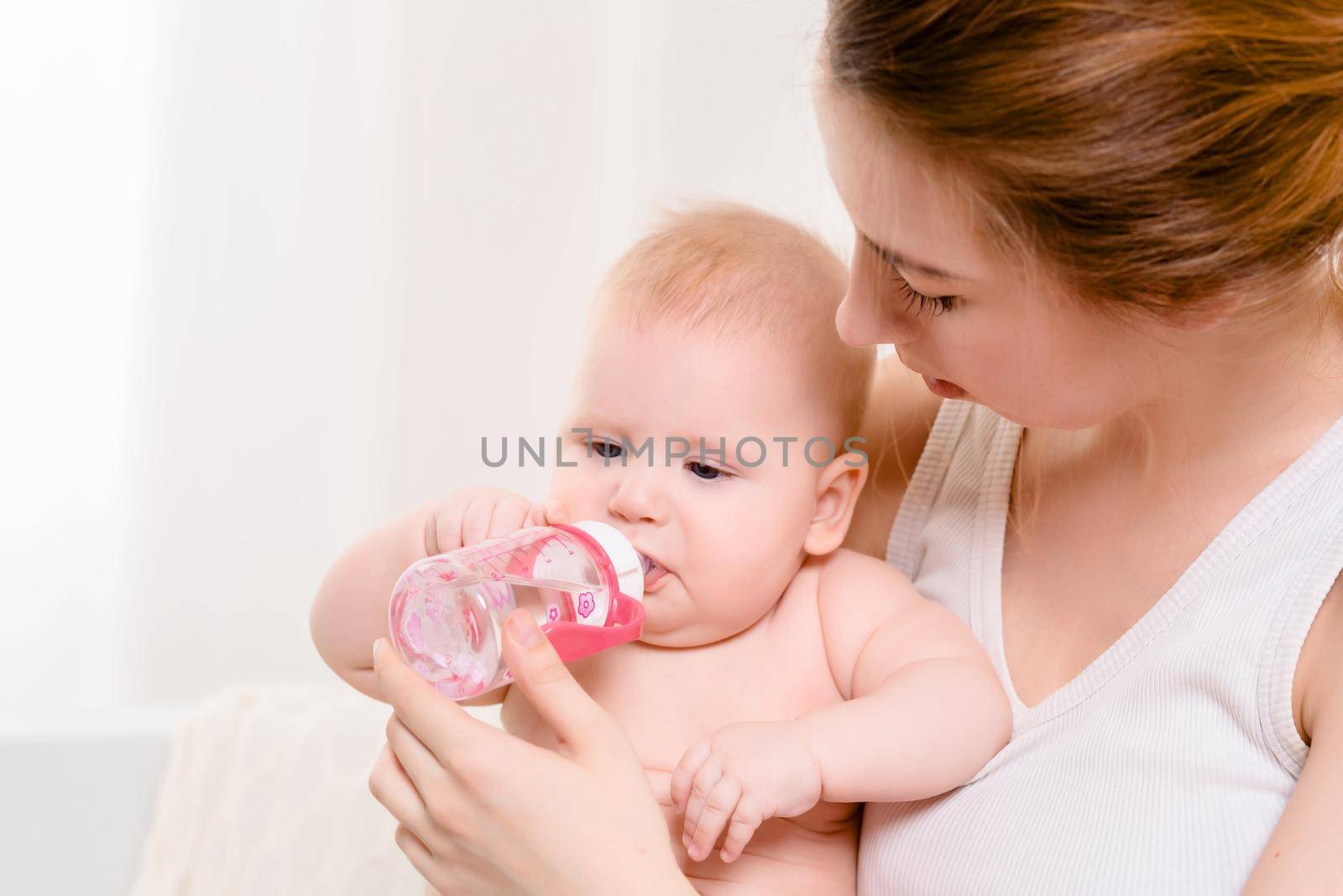Feeding Baby. Baby eating milk from the bottle. Mother Feeds Her Newborn Baby