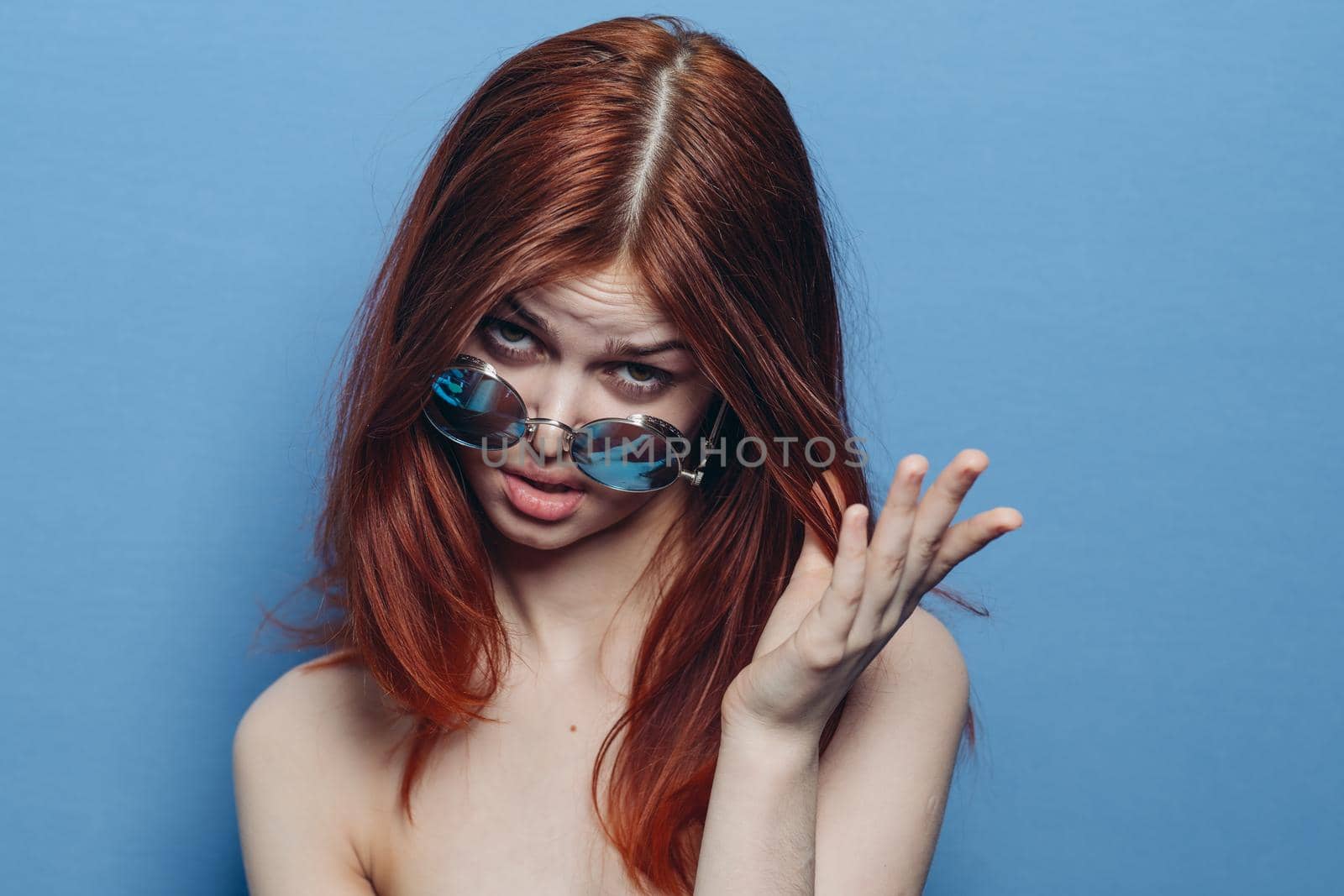 attractive woman with bare shoulders fashionable glasses blue background. High quality photo