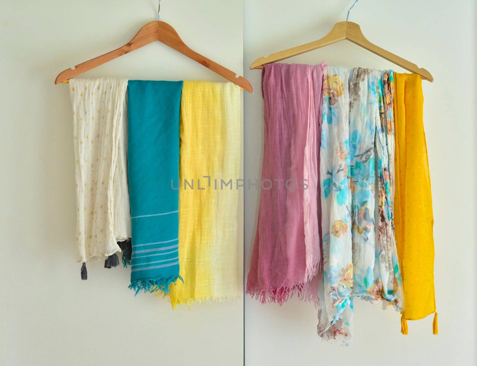 Multi-colored scarves hang on a hanger in a cupboard