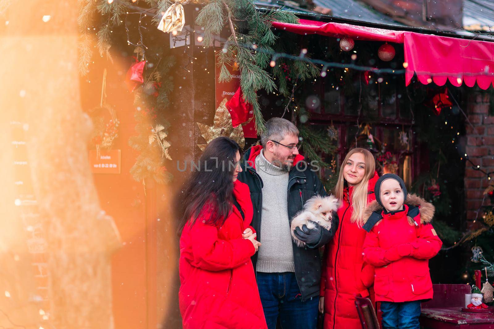 Happy family on the porch of the Christmas decorated house, snowing outdoor. Happy New Year and Merry Christmas. Magic winter