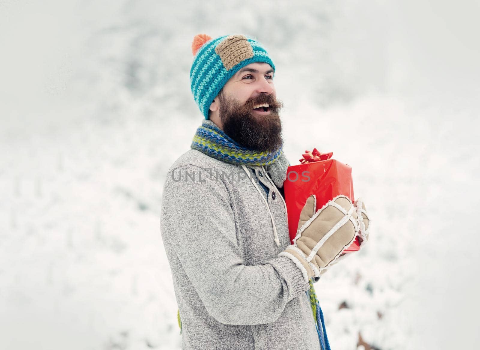 Hipster santa in cold snowy winter forest. Christmas happy man with beard hold present box. Bearded handsome man, Santa Claus with beard