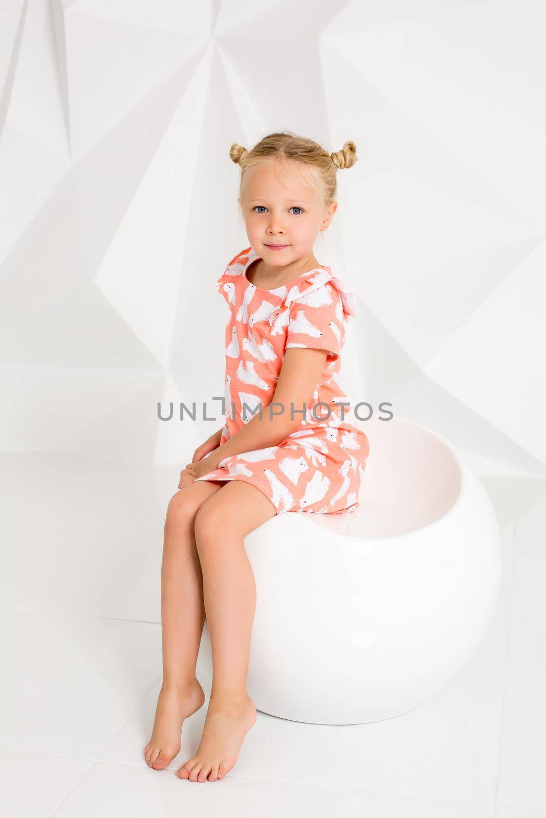 Beautiful little fashion model on white studio background. Portrait of cute girl posing in studio. Little blonde in bright summer dress