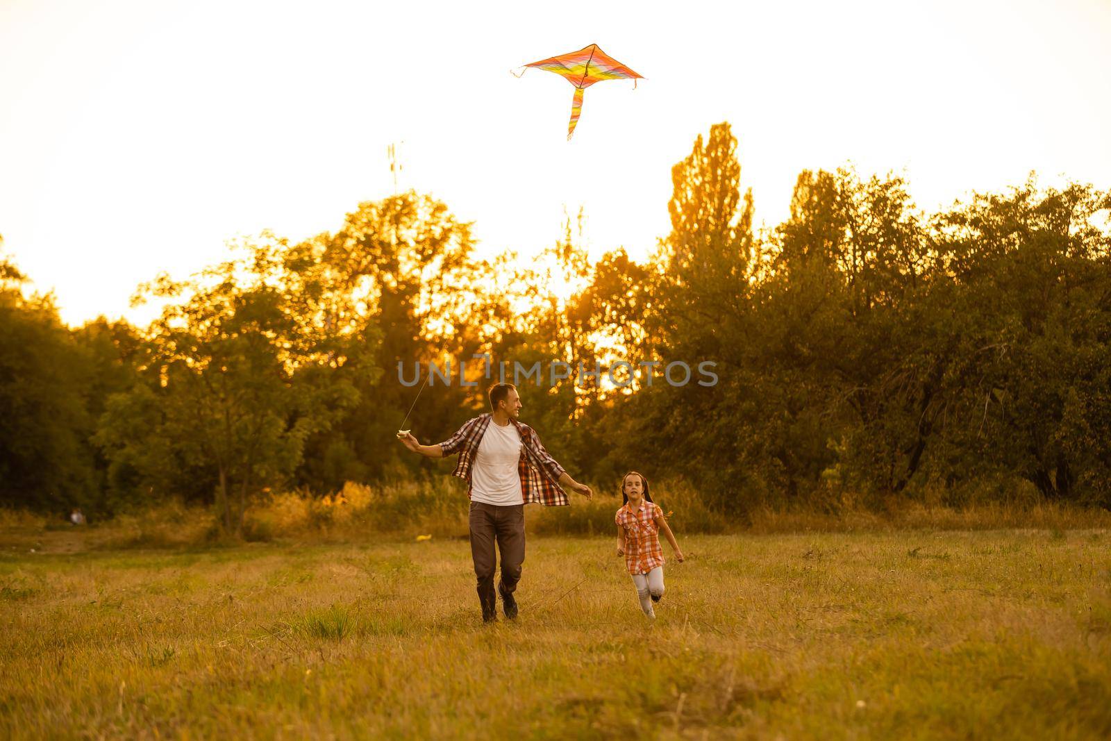 happy family father and child daughter run with a kite on meadow