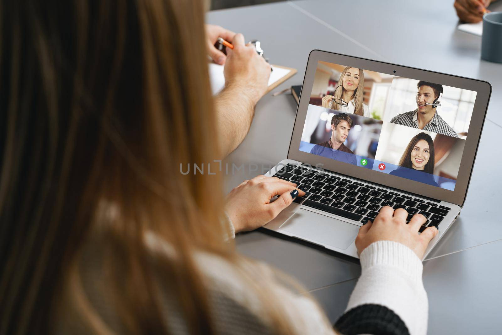 A girl is communicating via video call with classmates on laptop at home, online education