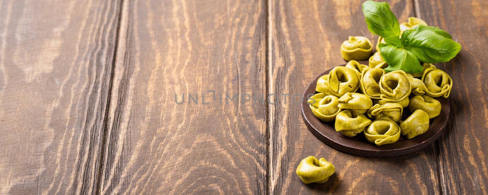 Homemade Tortellini with spinach, cheese and ricotta on wooden board. Healthy italian food concept with copy space. Banner.