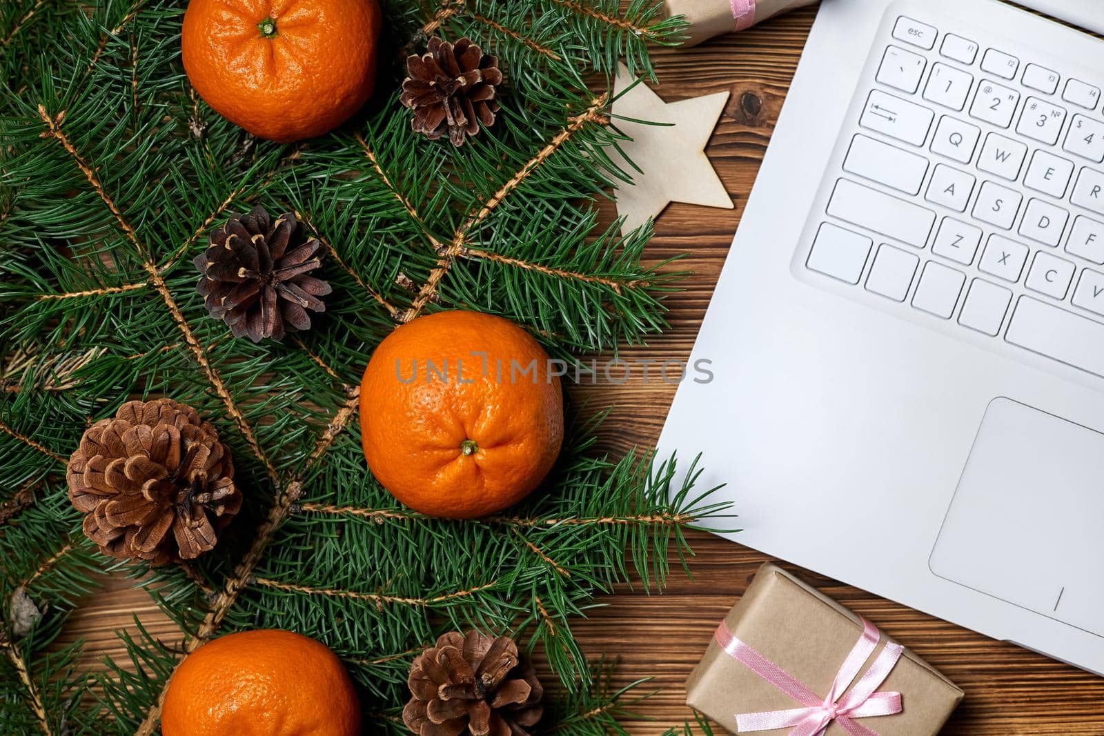 Christmas composition of open notebook, fir branches, pine cones and tangerines on wooden background
