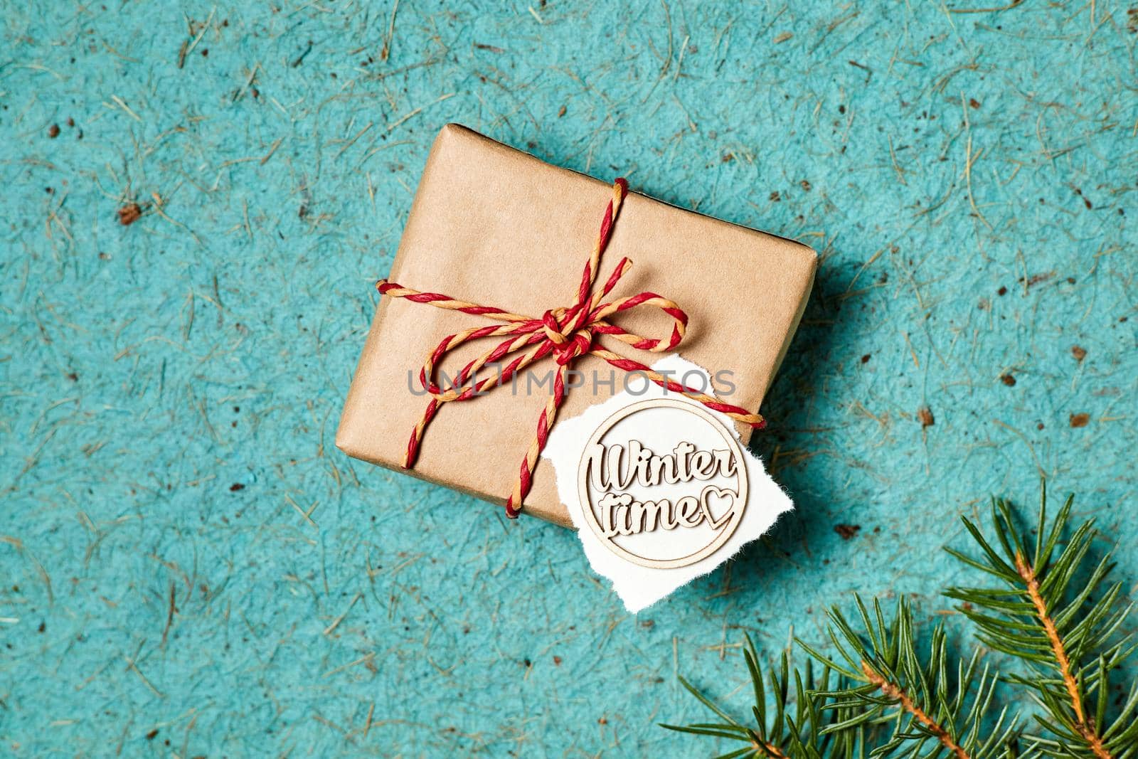 Close-up of Christmas gift box with winter time inscription on a blue background decorated with fir branches by marketlan