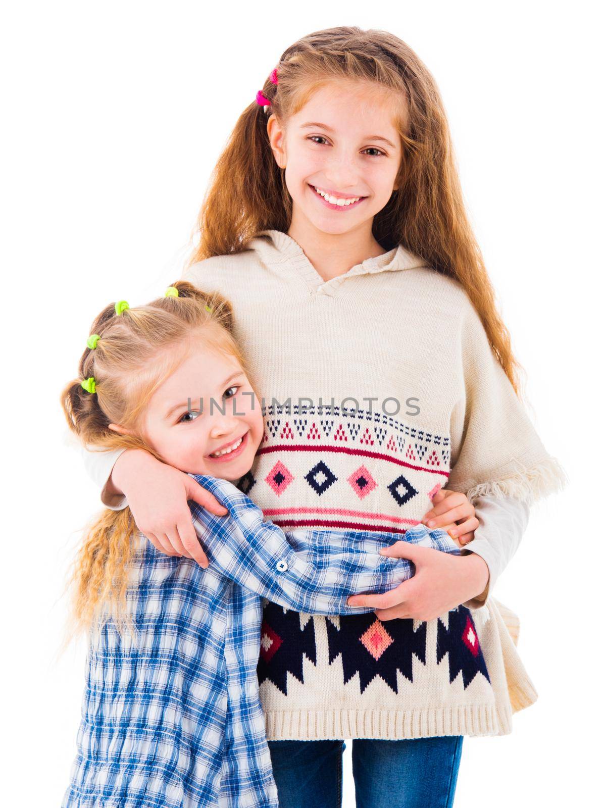 Two little girls sisters in casual clothes posing and hugging each other, isolated on white background
