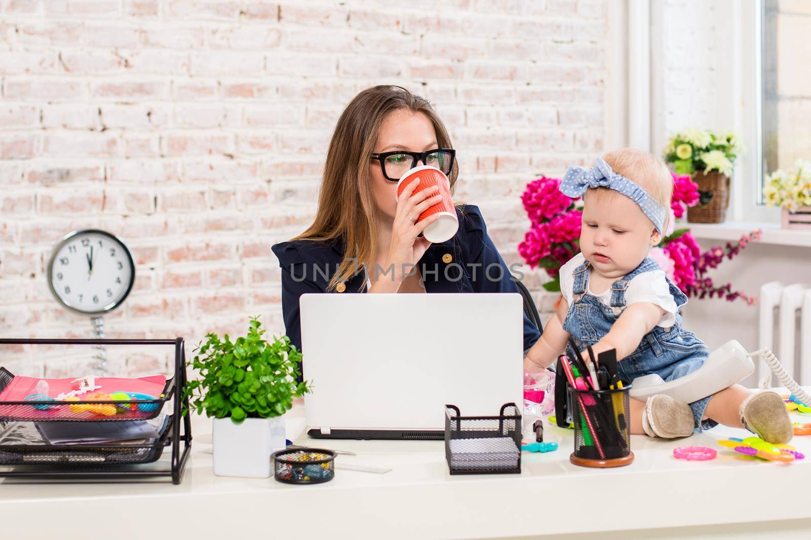 Businesswoman mother woman with a daughter working at the computer. At the workplace, together with a small child