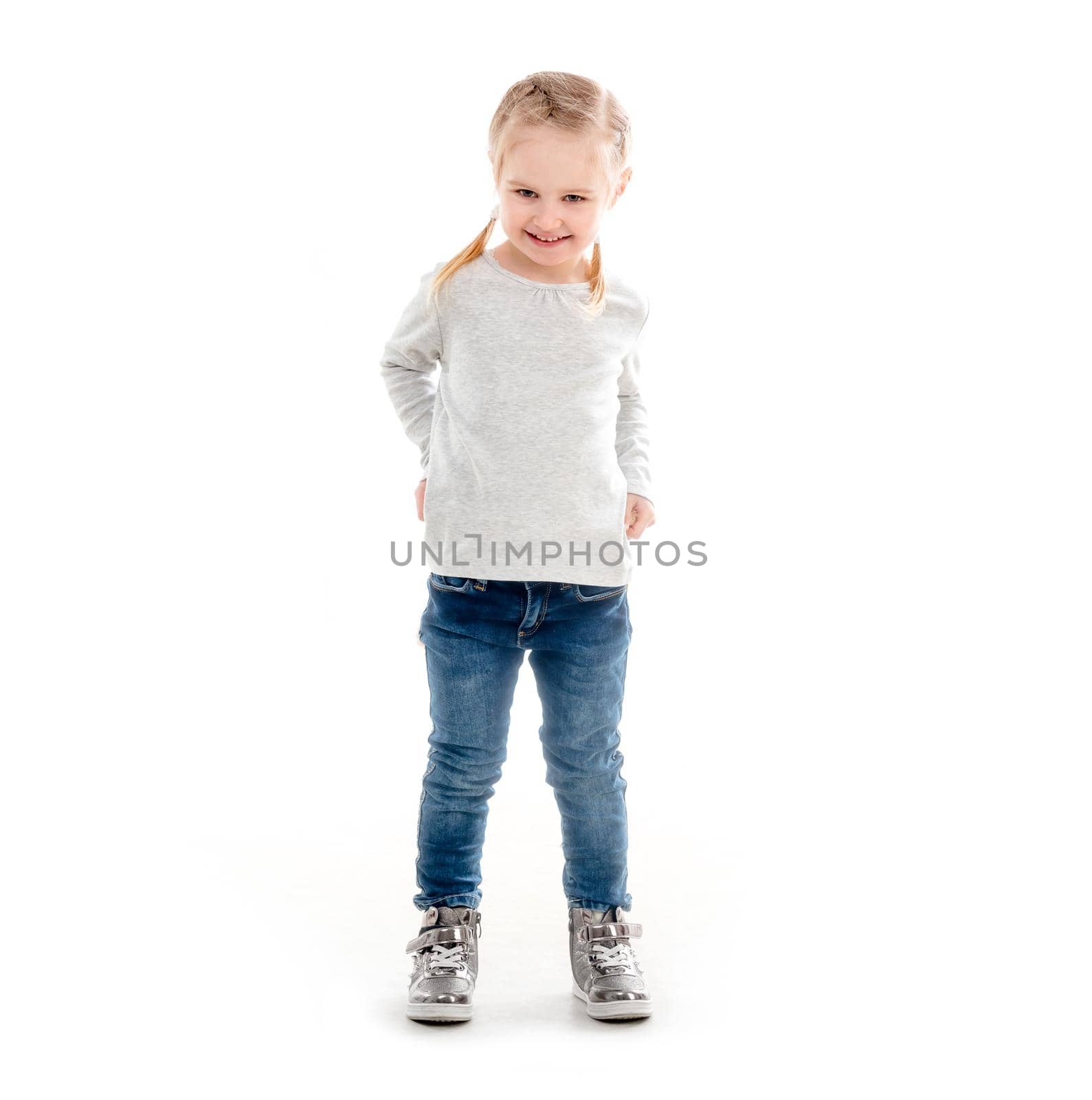 Lovely emotions of little girl stadning isolated on white background, wearning jeans and silvery shirt