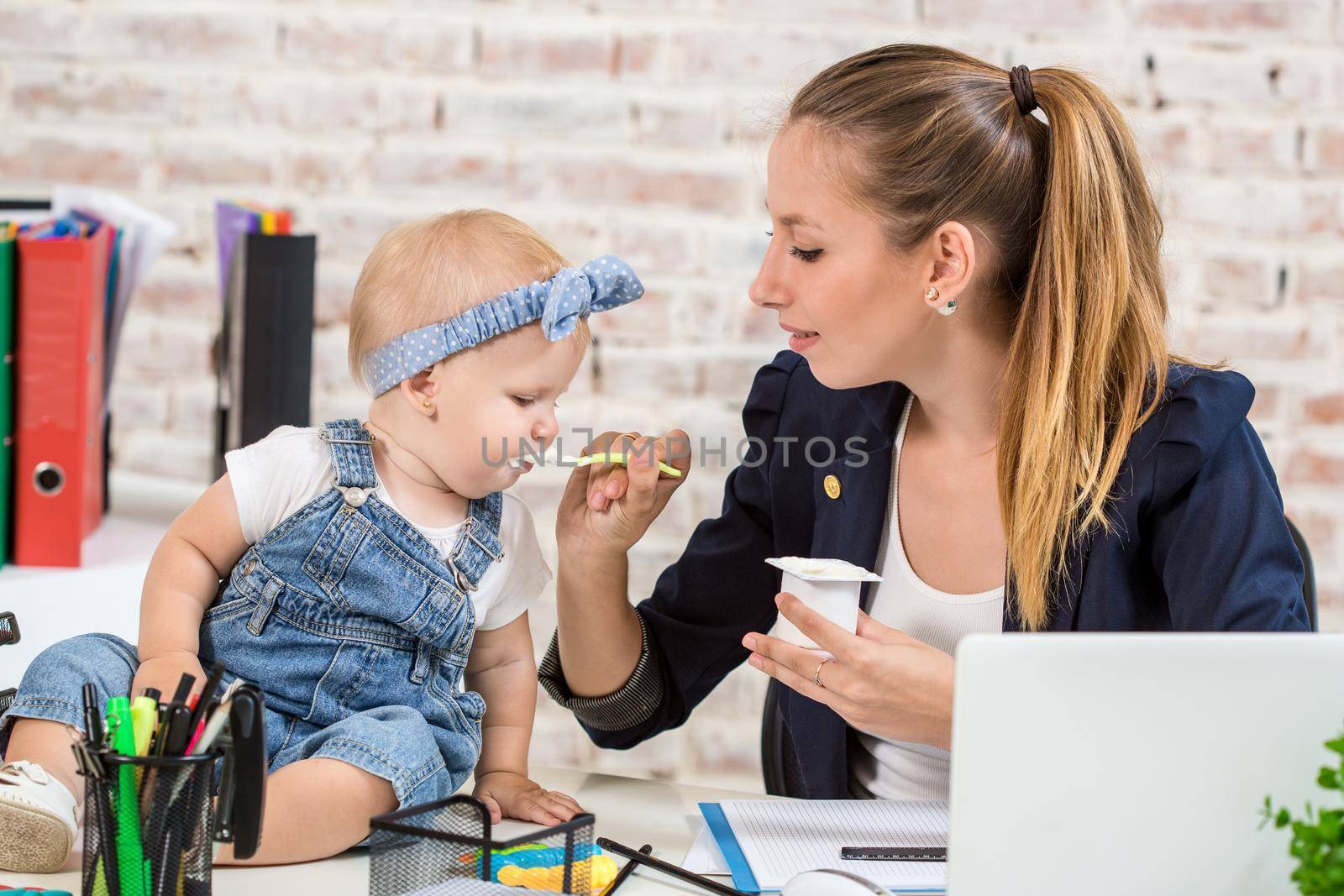 Mom and businesswoman working with laptop computer at home and playing with her baby girl. Horizontal shape, front view, waist up
