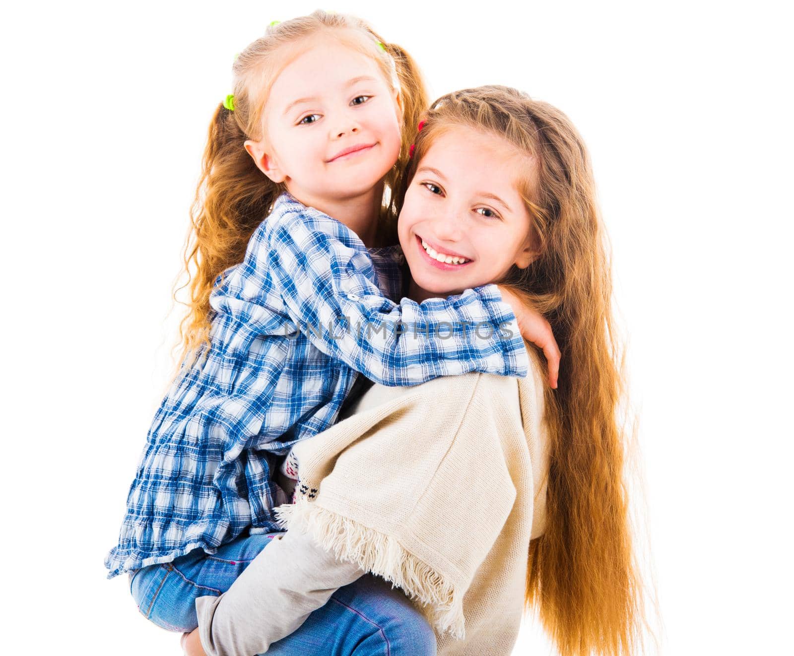Young girl holding in her arms her little sister and hapilly looking at camera, isolated on white background