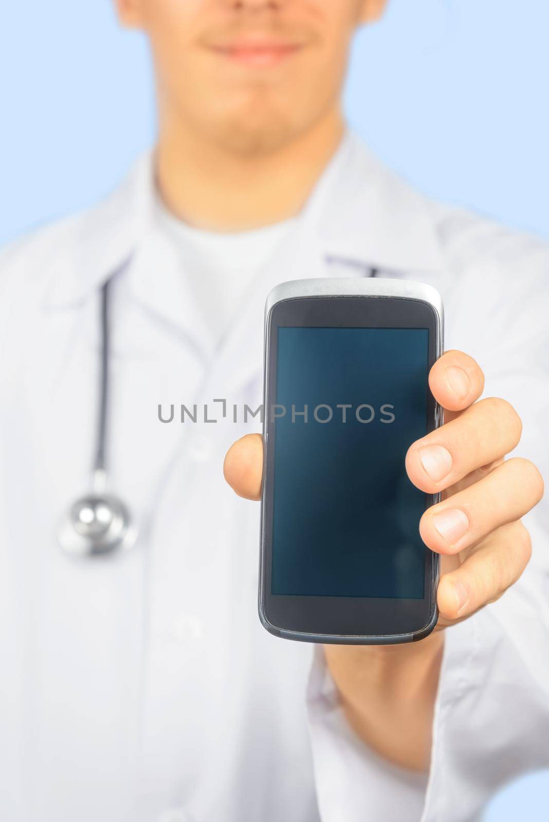 Smiling man doctor is showing mobile phone screen, copy-space