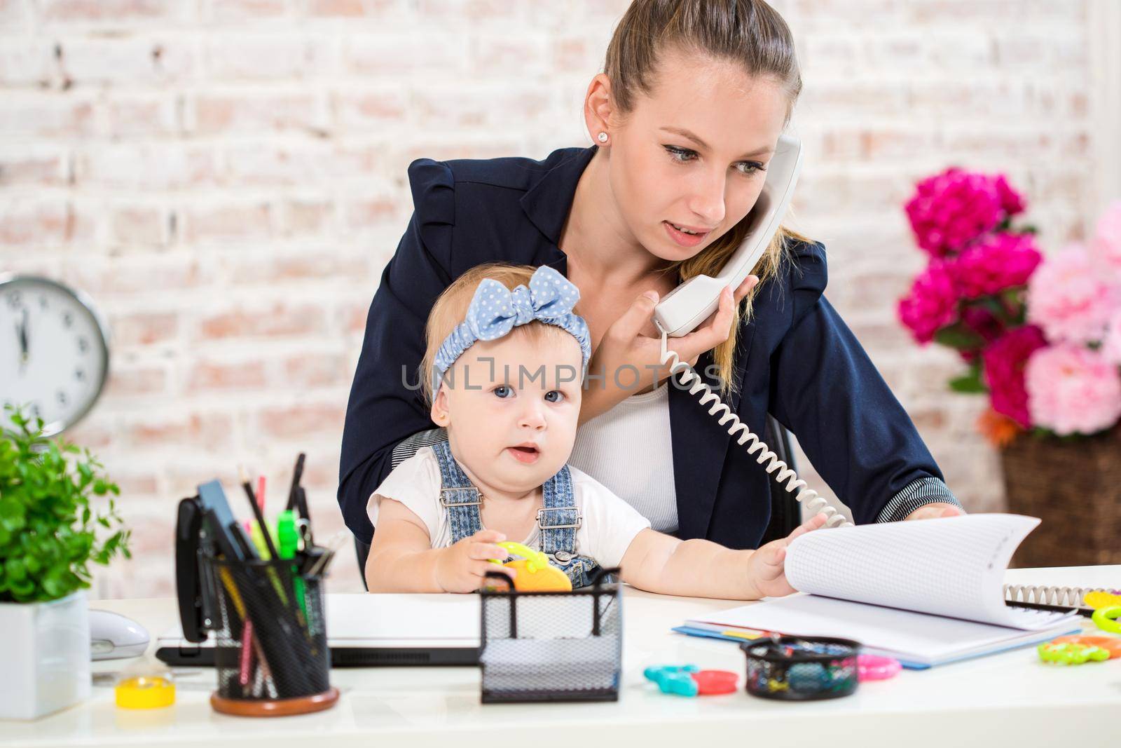 Family Business - telecommute Businesswoman and mother with kid is making a phone call. At the workplace, together with a small child