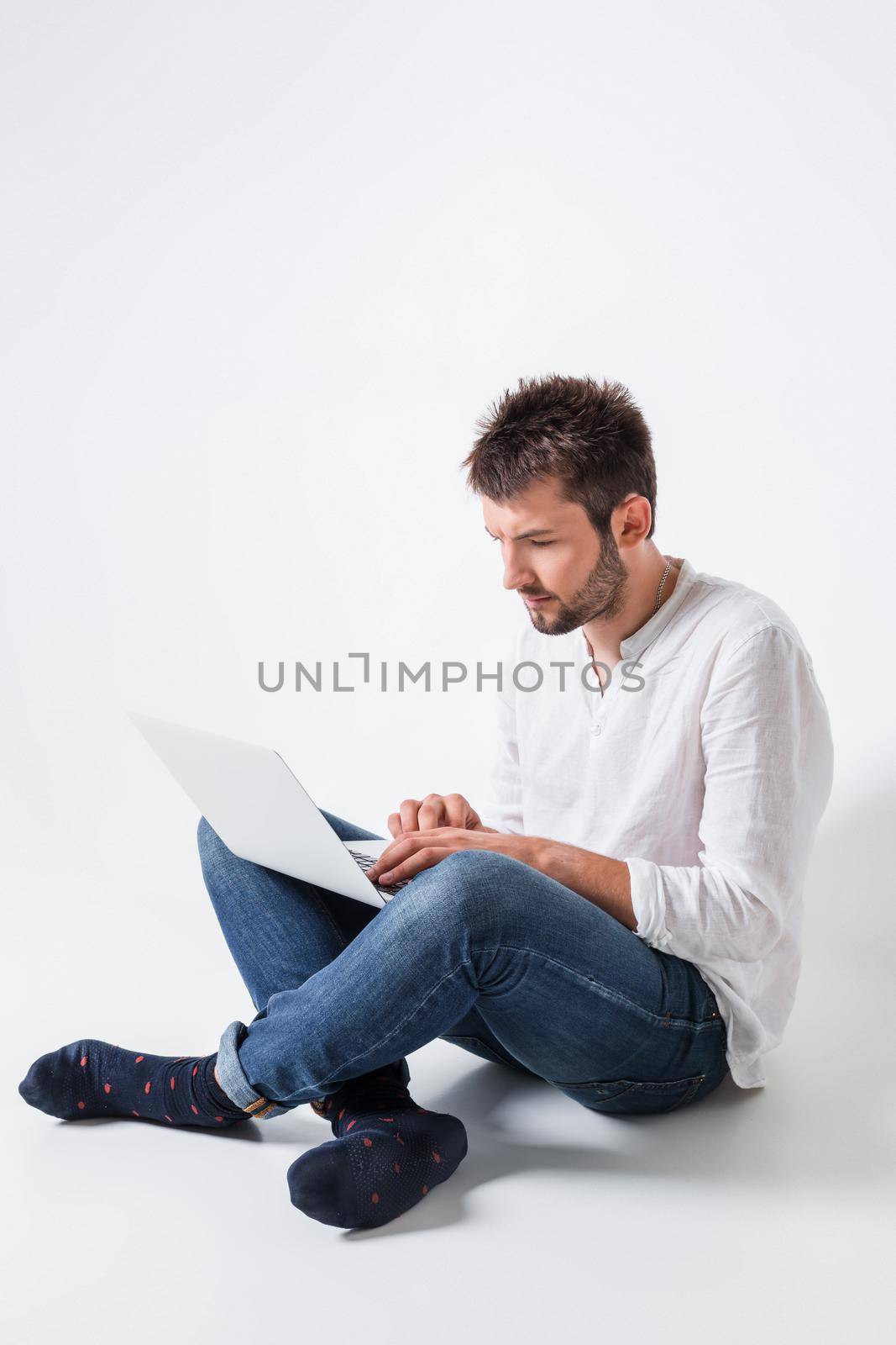 a young man in casual clothes working on a laptop.