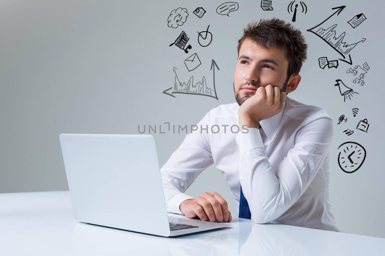 young man thinking uses a laptop computer while sitting at a table. Office clothing