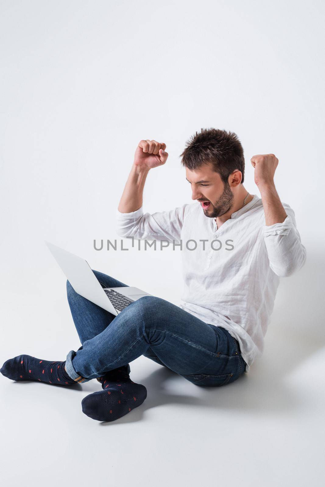 a young man in casual clothes working on a laptop. glad hands up