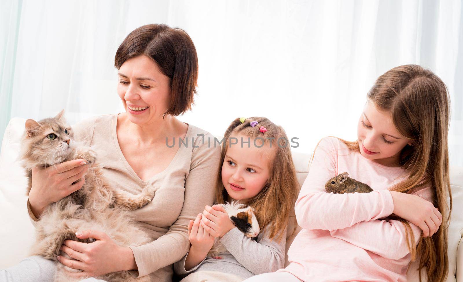 Mother and two daughters holding their favorite pets on hands. by GekaSkr