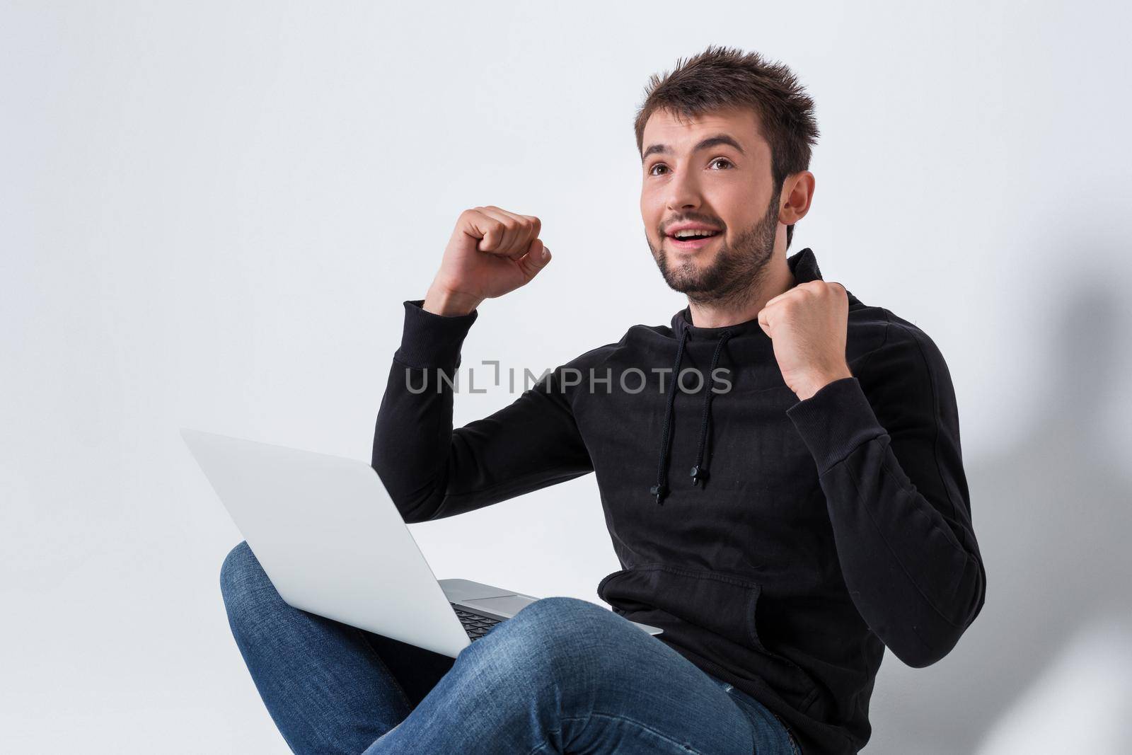 a young man in casual clothes working on a laptop. glad hands up