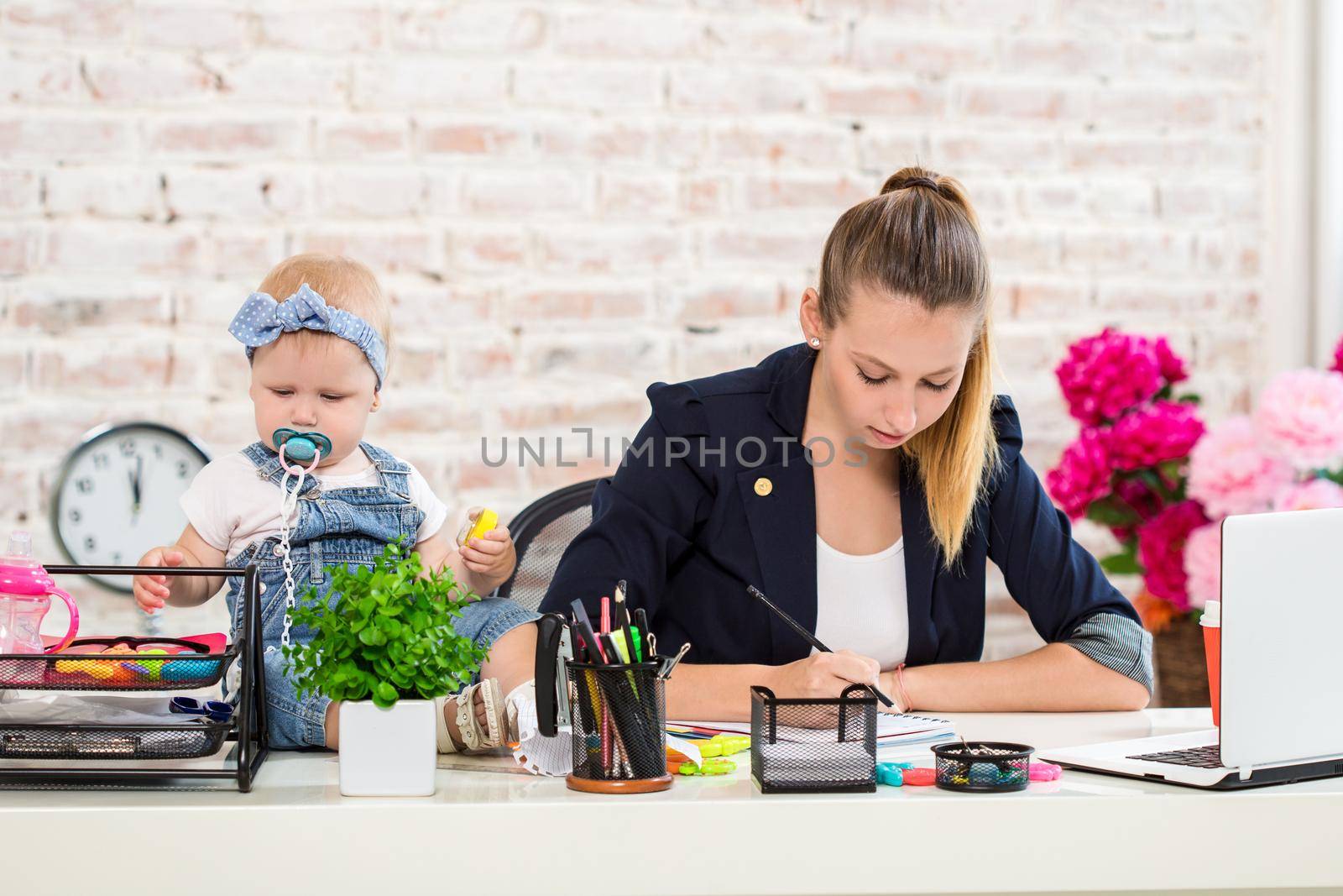 Mom and businesswoman working with laptop computer at home and playing with her baby girl. by nazarovsergey