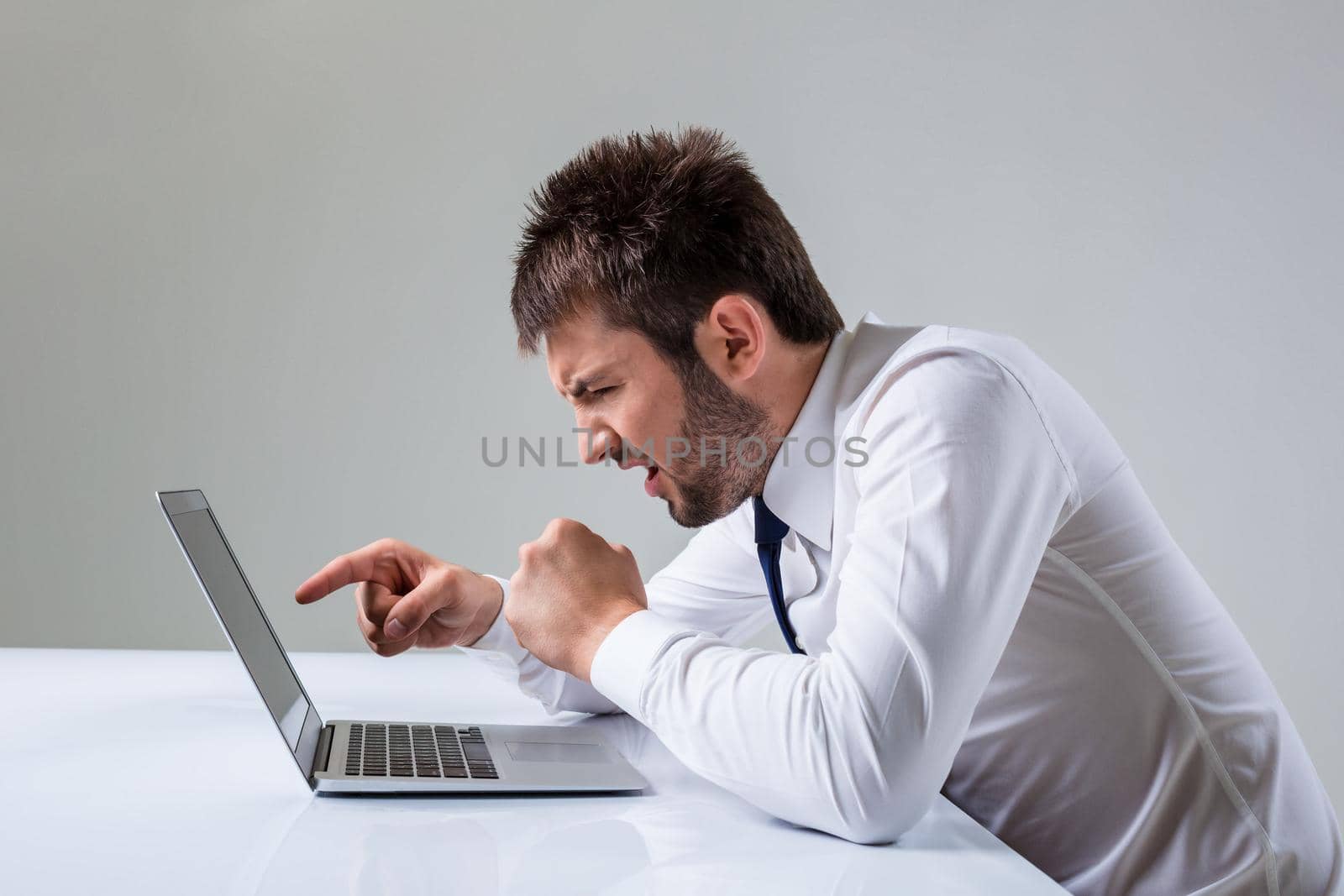 the young man is nervous and poke a finger. It uses a computer while sitting at a table. Office clothing