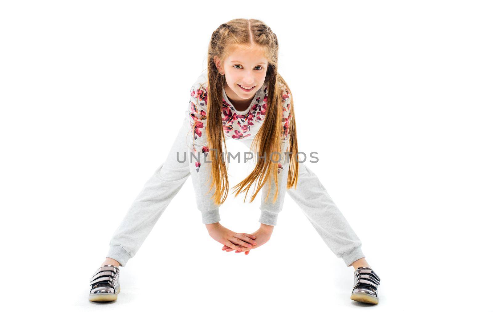 Little girl do forward bend exercise in grey sportwear, isolated on white background. Healthy lifestyle