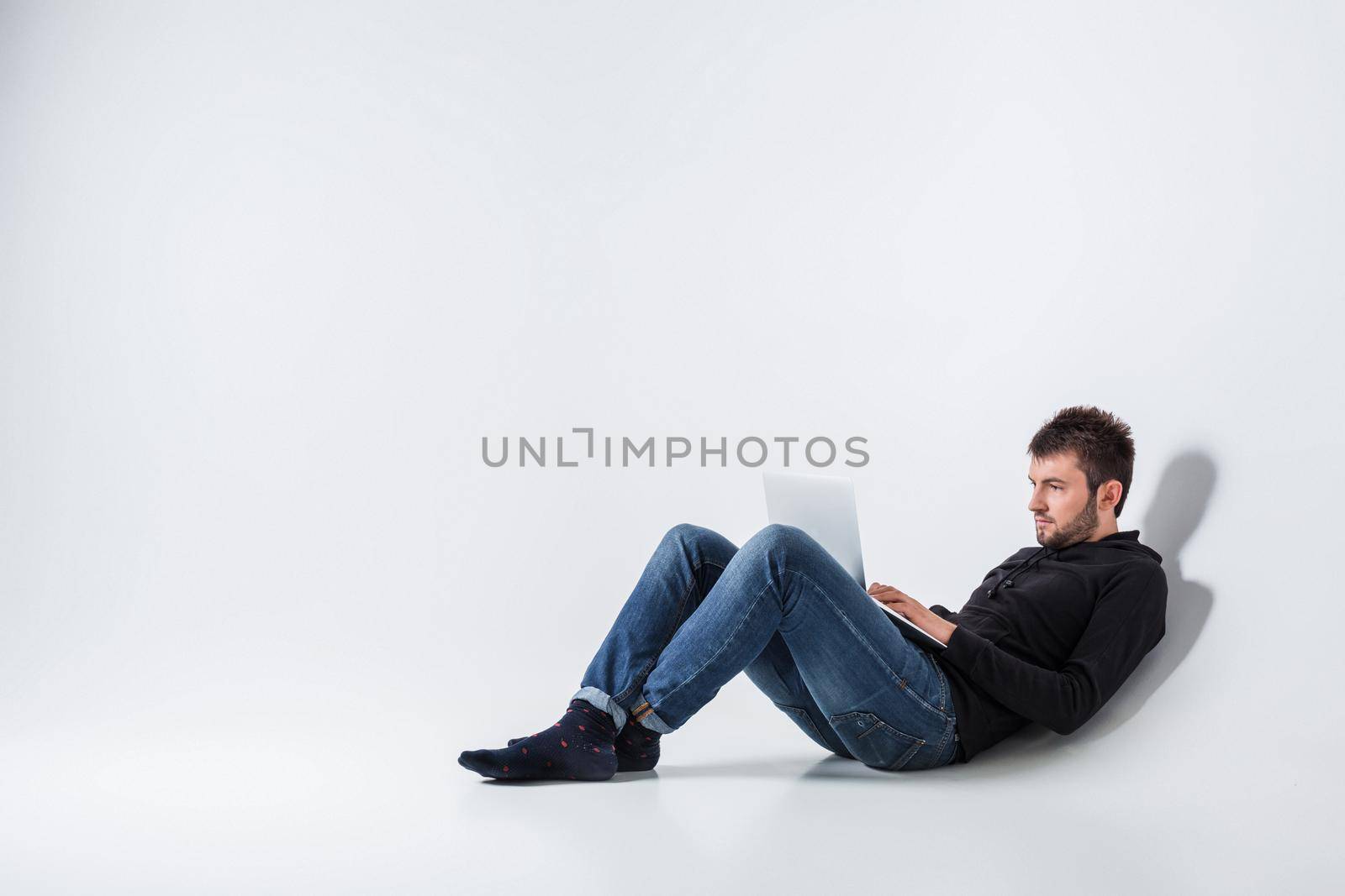 a young man in casual clothes working on a laptop.