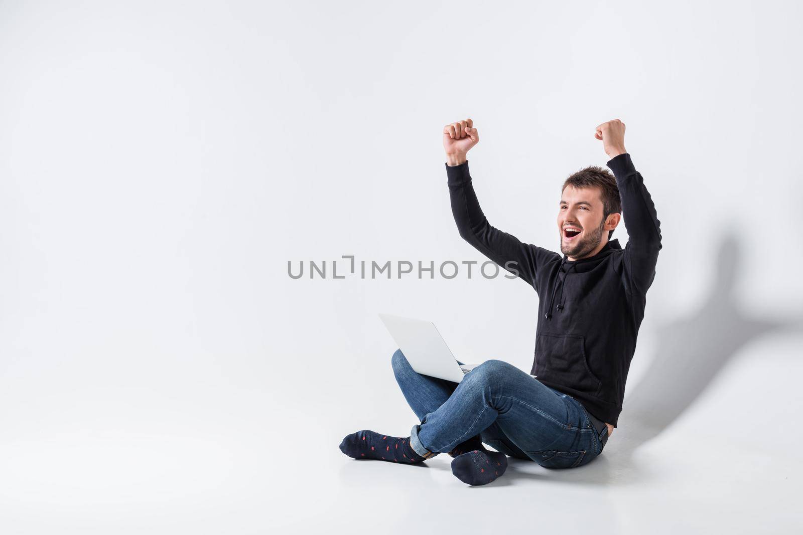 a young man in casual clothes working on a laptop. glad hands up