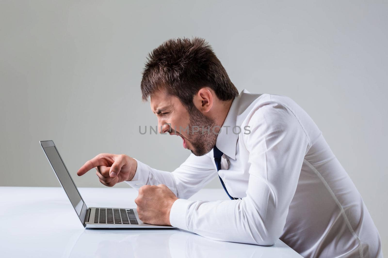 the young man is nervous and poke a finger. It uses a computer while sitting at a table. Office clothing