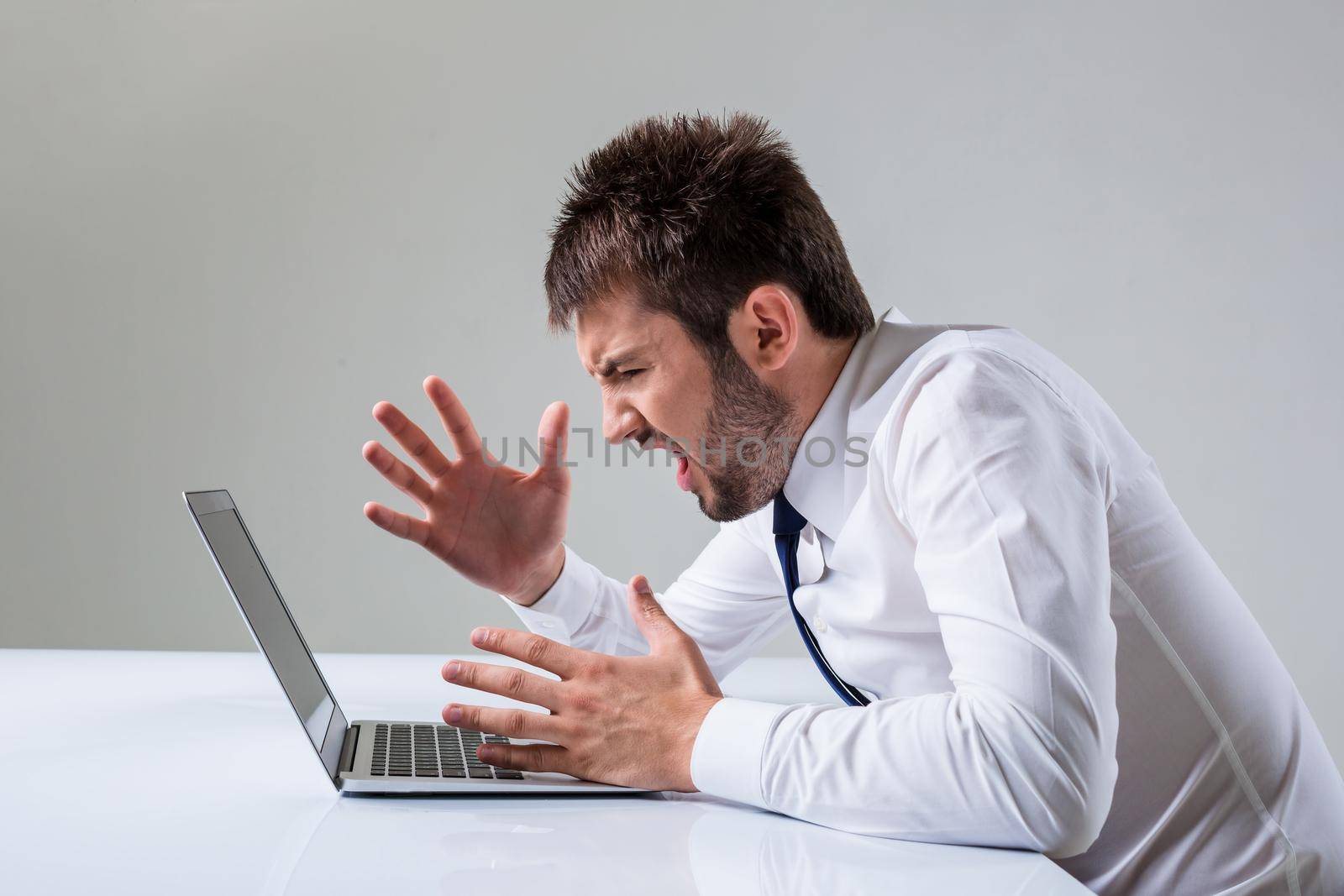 the young man is nervous. It uses a computer while sitting at a table. Office clothing