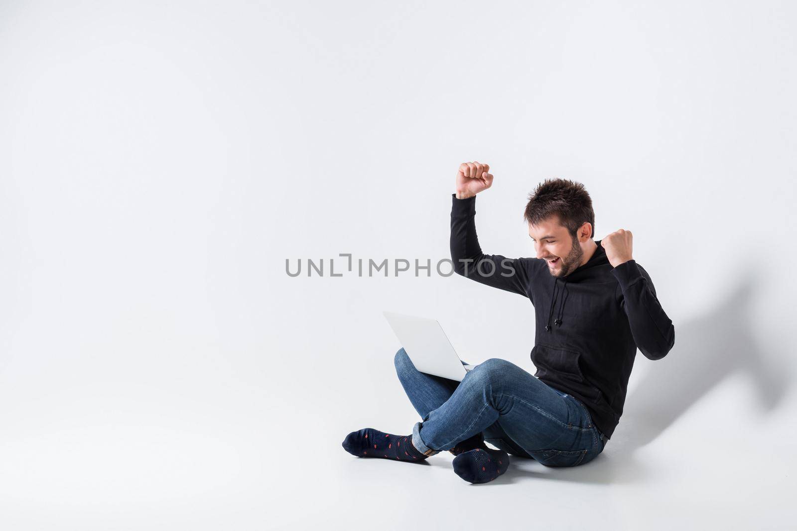 a young man in casual clothes working on a laptop. glad hands up