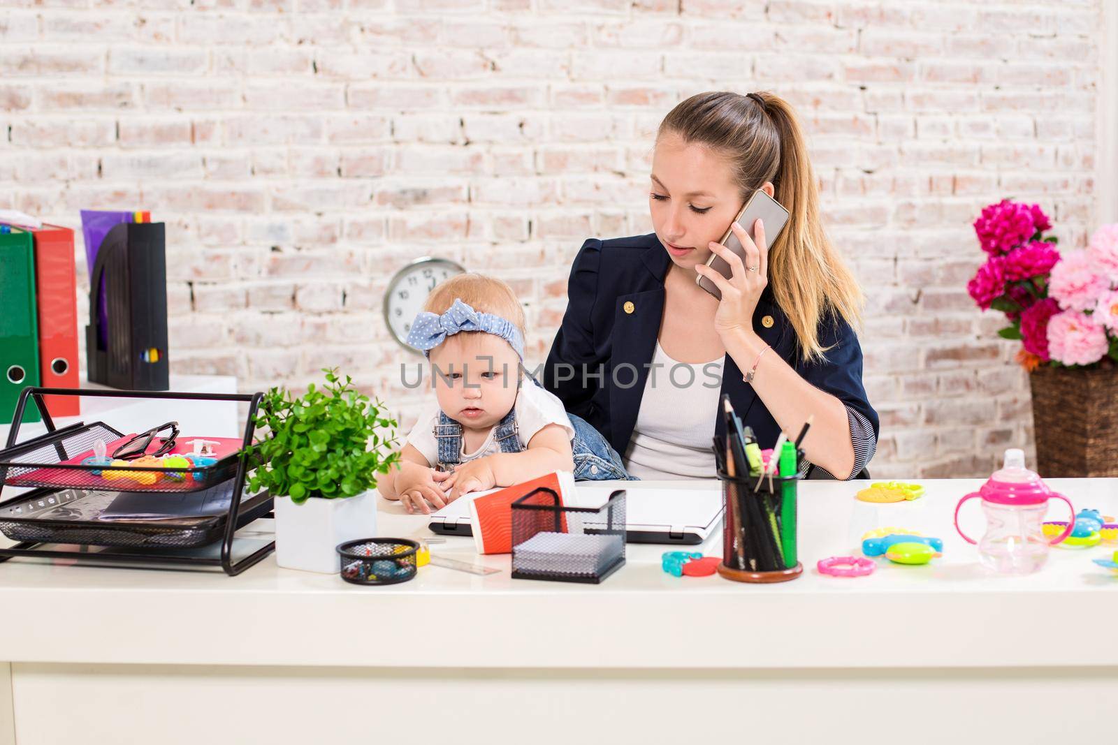 Family Business - telecommute Businesswoman and mother with kid is making a phone call. At the workplace, together with a small child