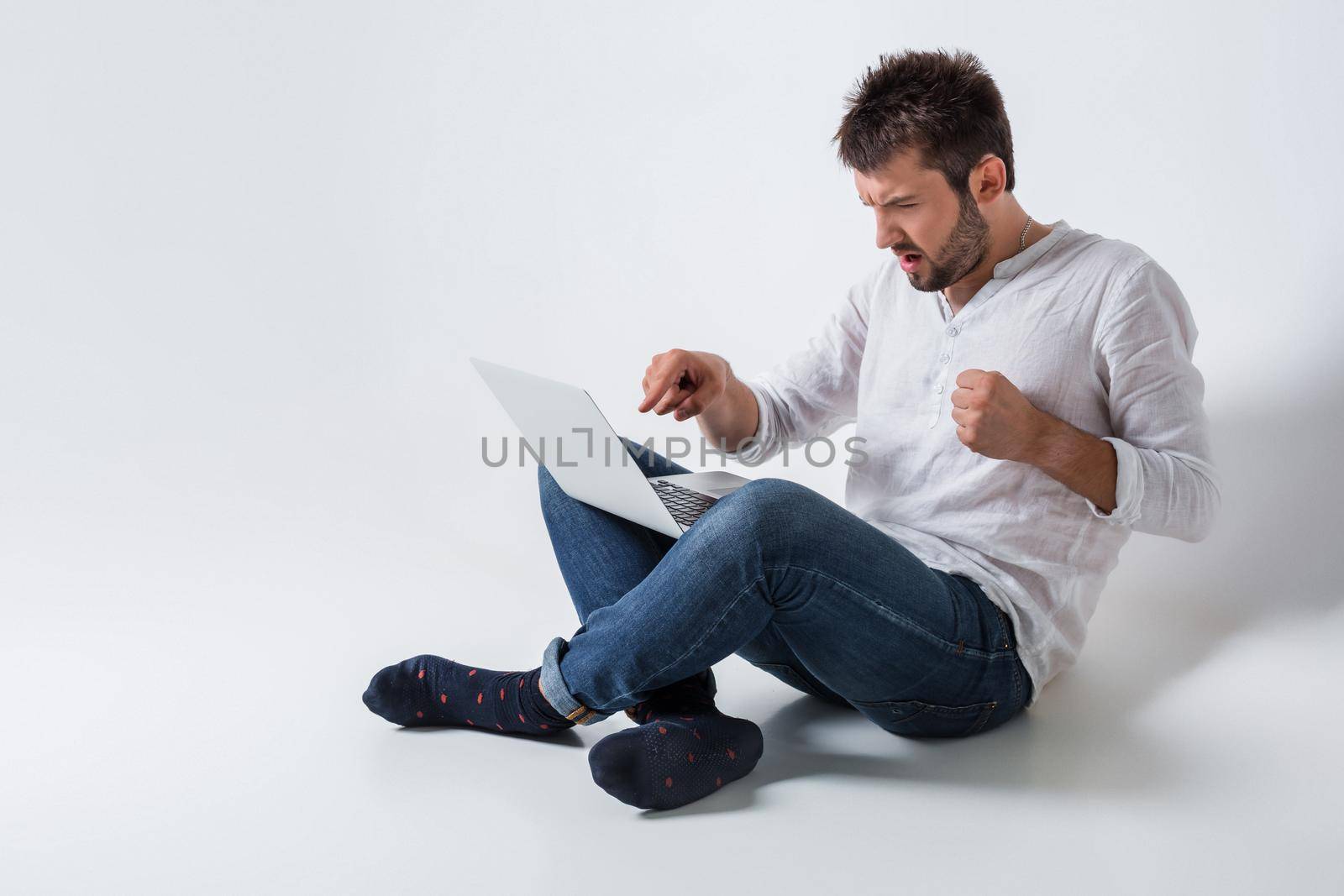 a young man in casual clothes working on a laptop. angry, a slap in the screen