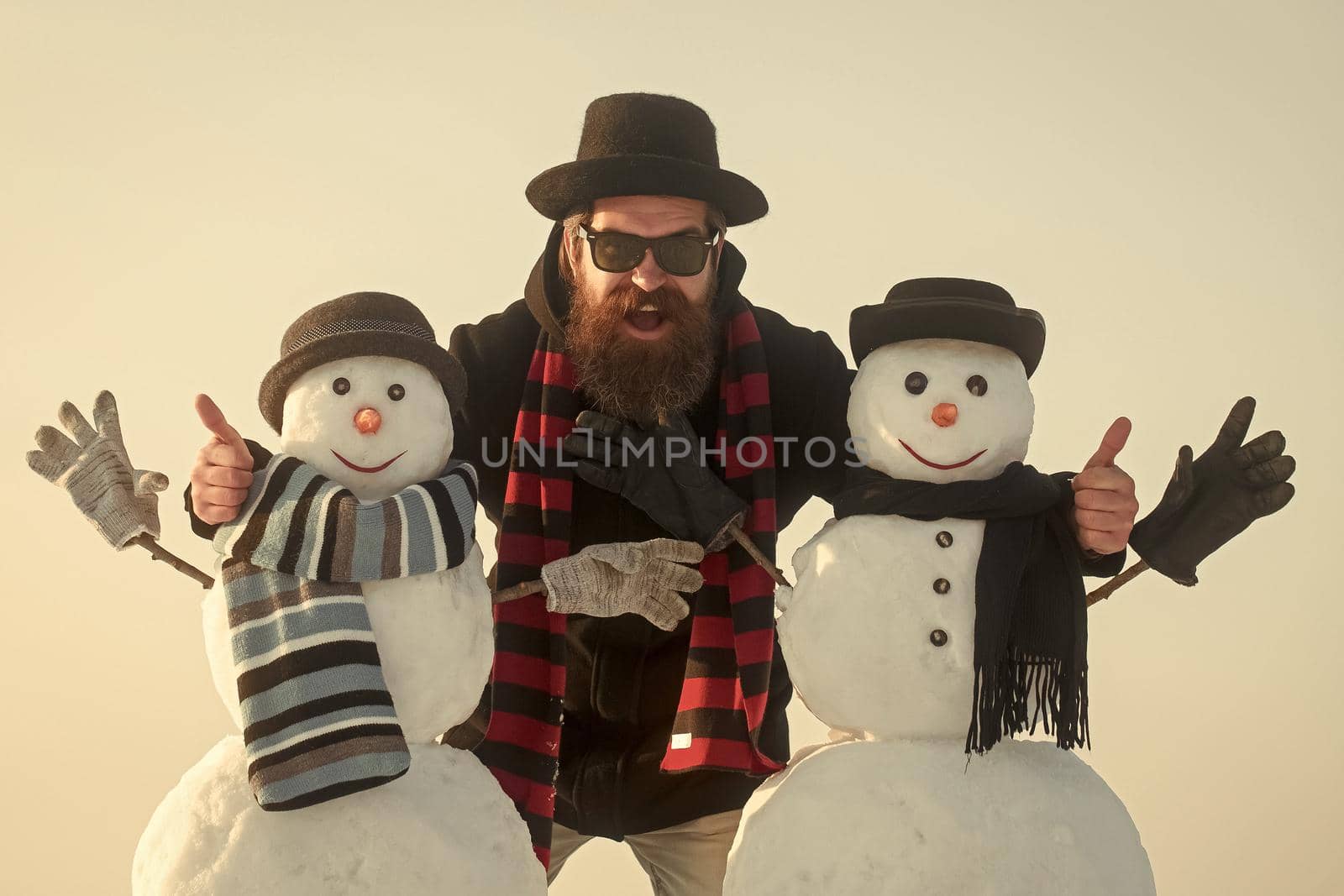 Man and snowman, winter holiday celebration outdoor. Winter leisure and winter season. Funny santa man with snowman in black hat