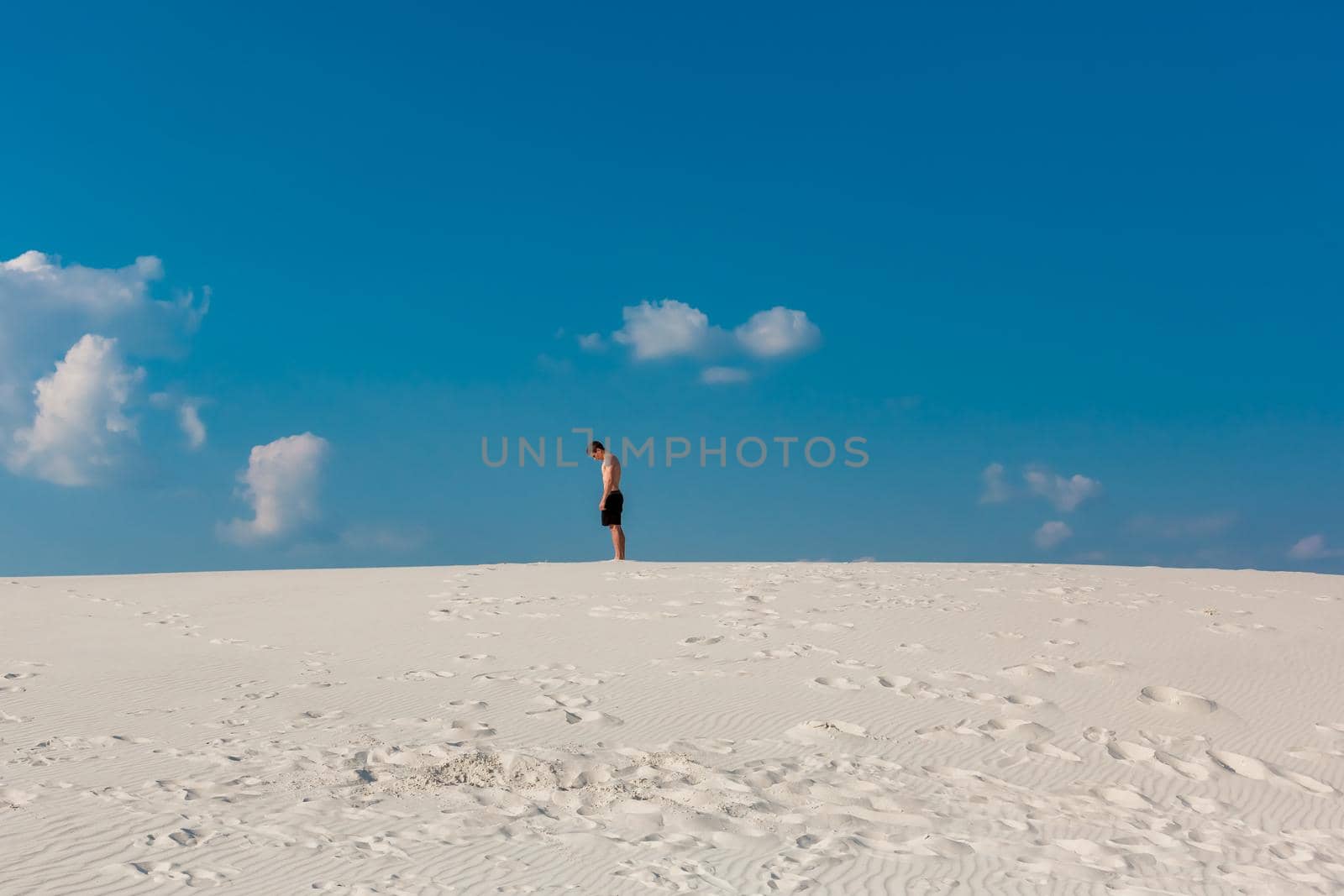 Young sporty man want doing acrobatic exercises on the sand near river. Portrait of young parkour man