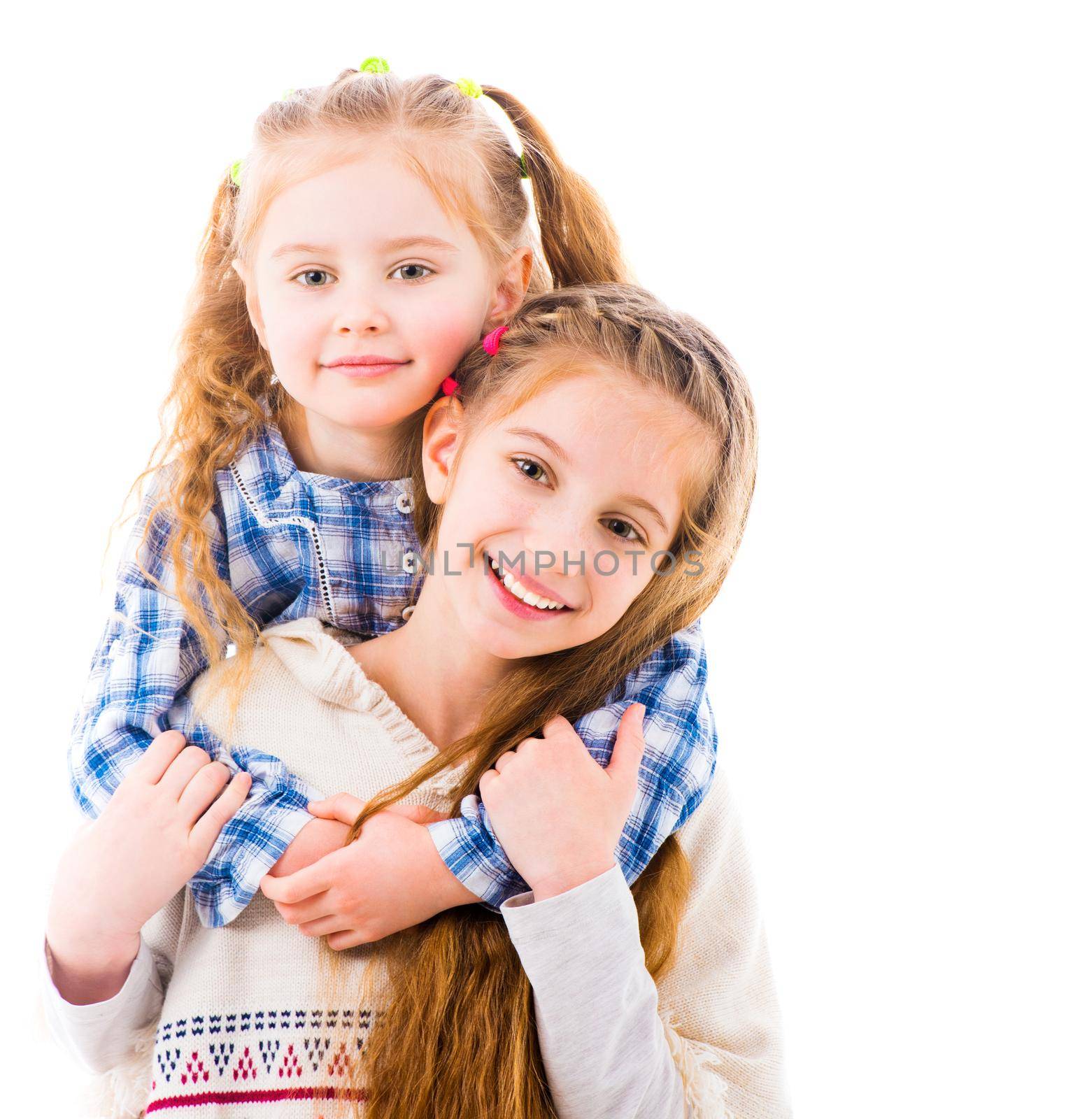 Two little girls sisters in casual clothes posing and hugging each other, isolated on white background